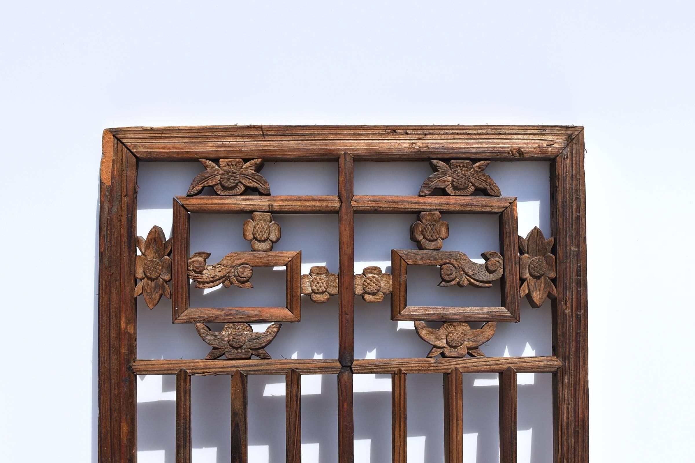 A nice natural finish window screen from the 19th century. 

The base design is a geometric one, with the top and mid-section in dragon scrolls inset by carved flowers. The flower is begonia, symbolizing happiness and prosperity. 

The