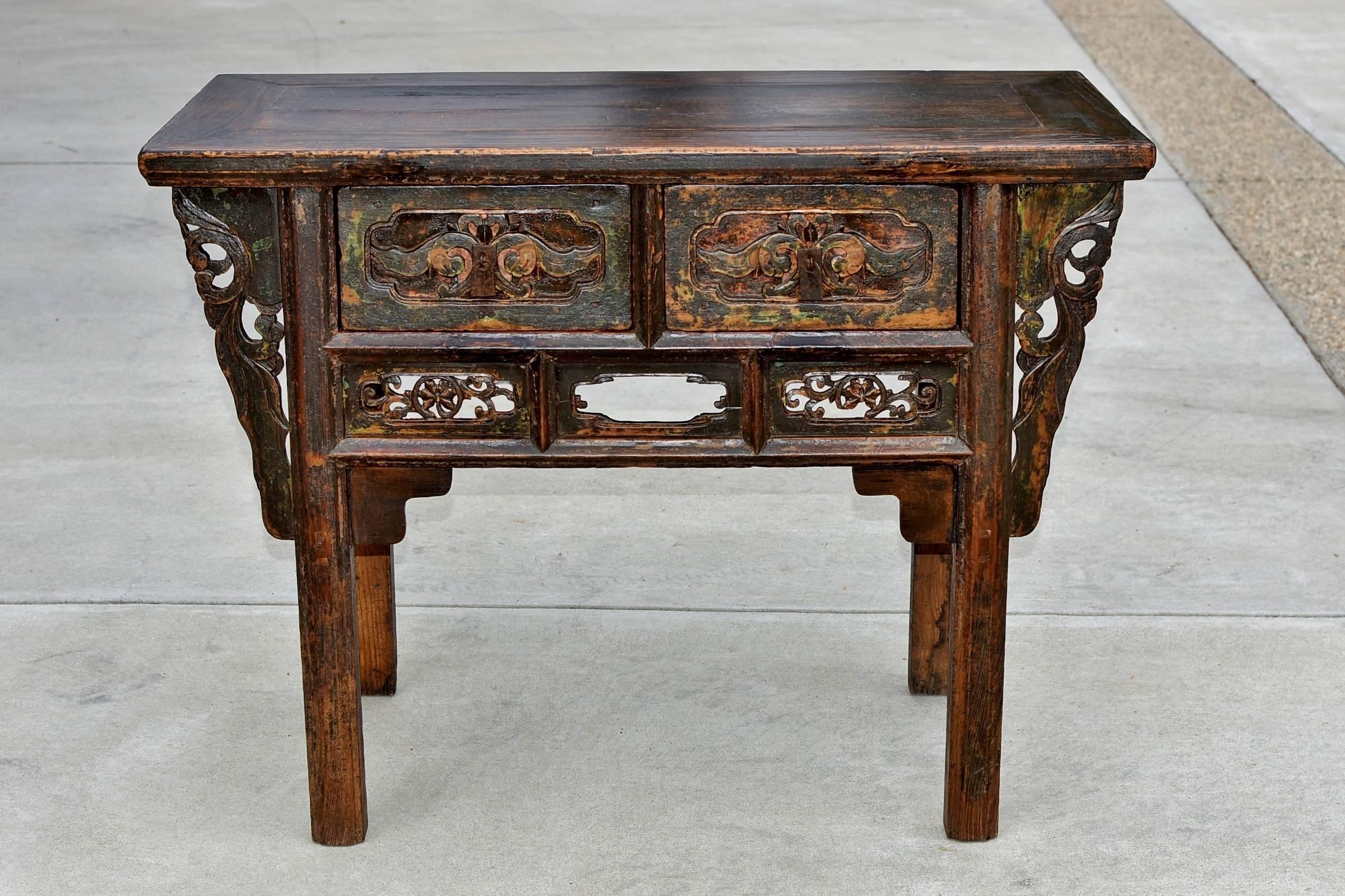 A beautiful antique table that is the perfect scale. It is carved with northern style peonies and scrolls. The chunkiness of the flowers on the drawer front contrasts nicely with the delicateness of the scrolls underneath. More scroll works are seen