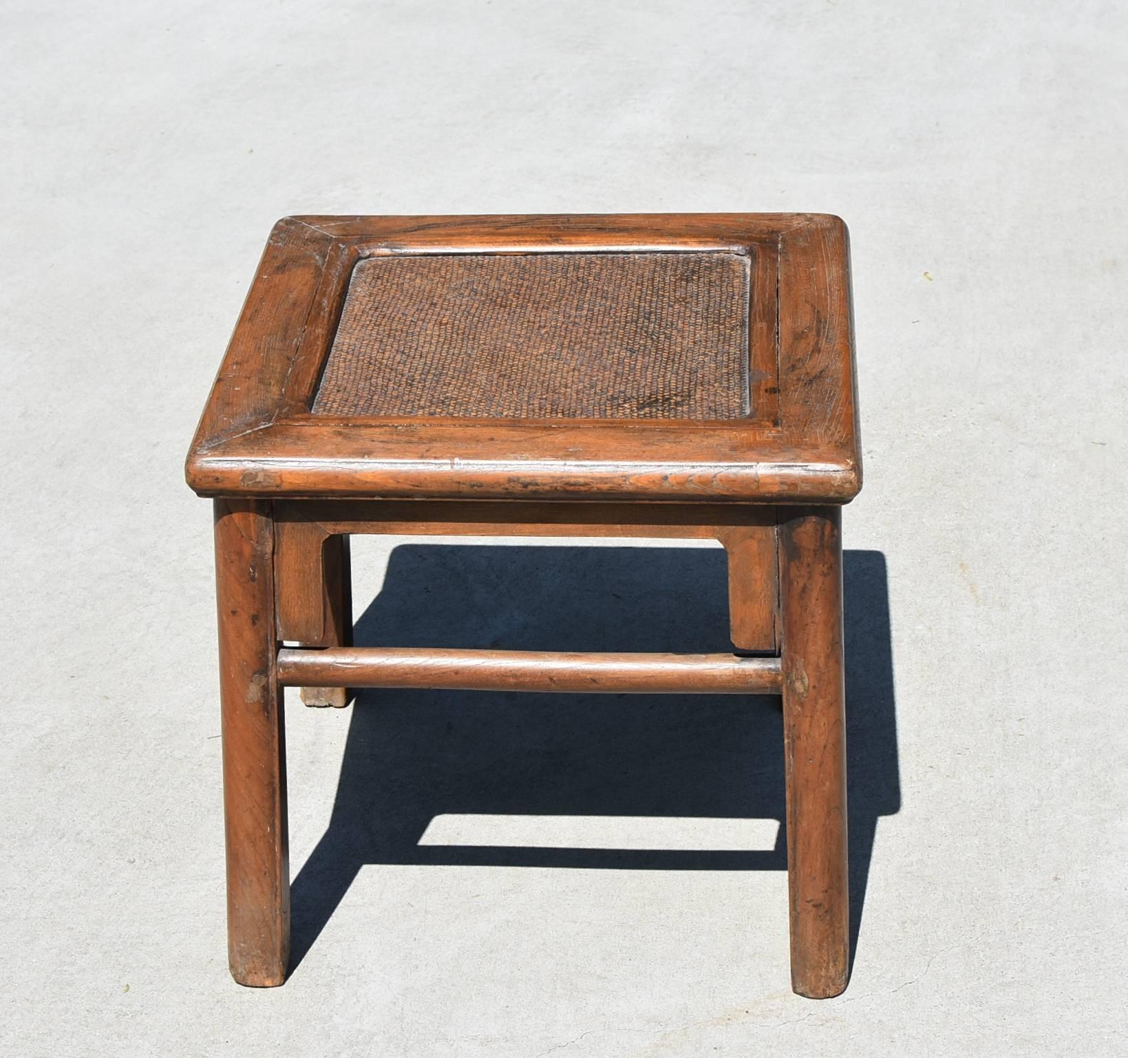 A 19th century Chinese stool. It has all the rustic charm of country and the nice lines of Ming furniture. The top is constructed with a floating panel with a rattan seat inset, a typical southern make. Round legs soften the lines and add elegance.