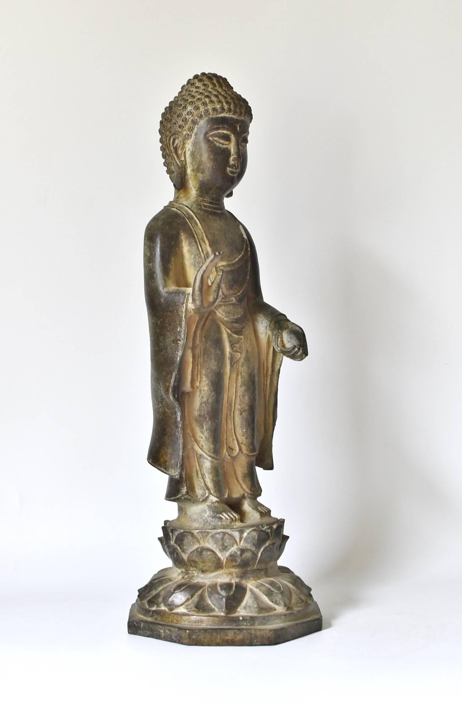 A beautiful bronze standing Buddha statue on a lotus stand. The style of the piece is of the Tang dynasty era, with a full face, long ear lobes and scrolled hair style. Beautiful, finely defined facial features convey a sense of calm and serenity.