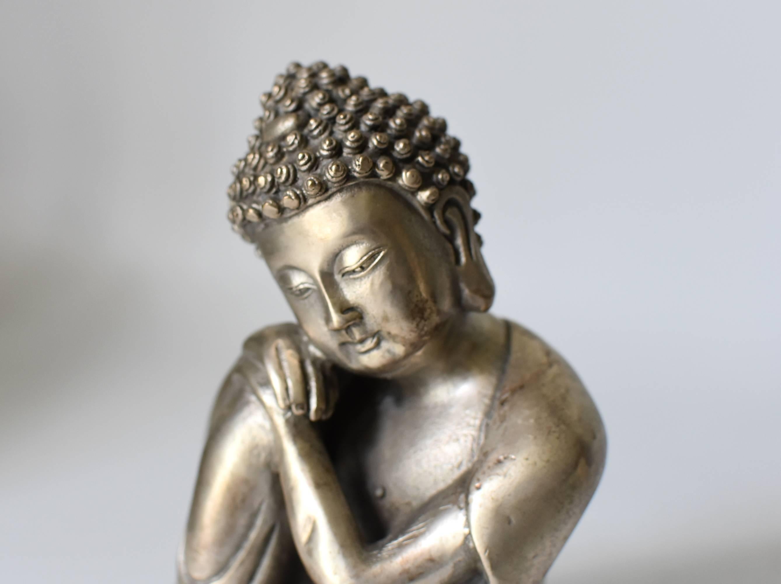 A beautiful silvered brass metal contemplative Buddha. This is a rare version of Buddha depiction, in an unique style. Through fine craftsmanship, the statue conveys a sense of peace and calm. This piece is small and exquisite, perfect as a desk top