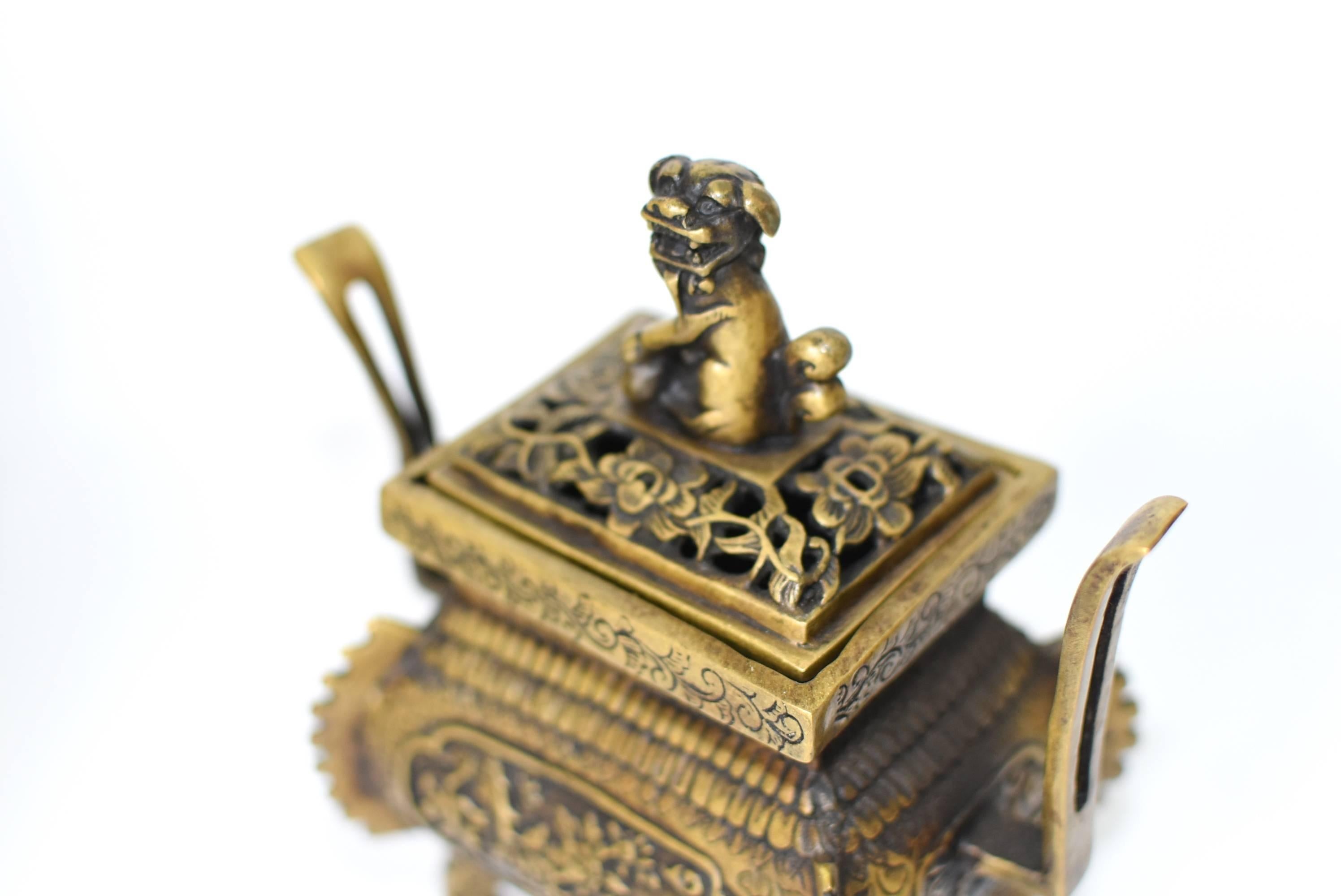 A beautiful, fully decorated incense burner. The burner has curved legs, a bombay style main compartment with an ancient fin pattern. The lid has a floral motif with an adorable foo dog as a finial. Embossed scrolls, flowers and foliage adorn the