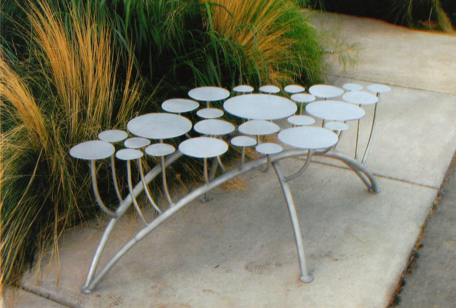 This unique backless bench designed and built by California artist Mark Oldland has a diamond-shaped seat made of 27 individual stainless steel disks attached to curved stainless steel legs. The bench can be placed indoors or outdoors and makes