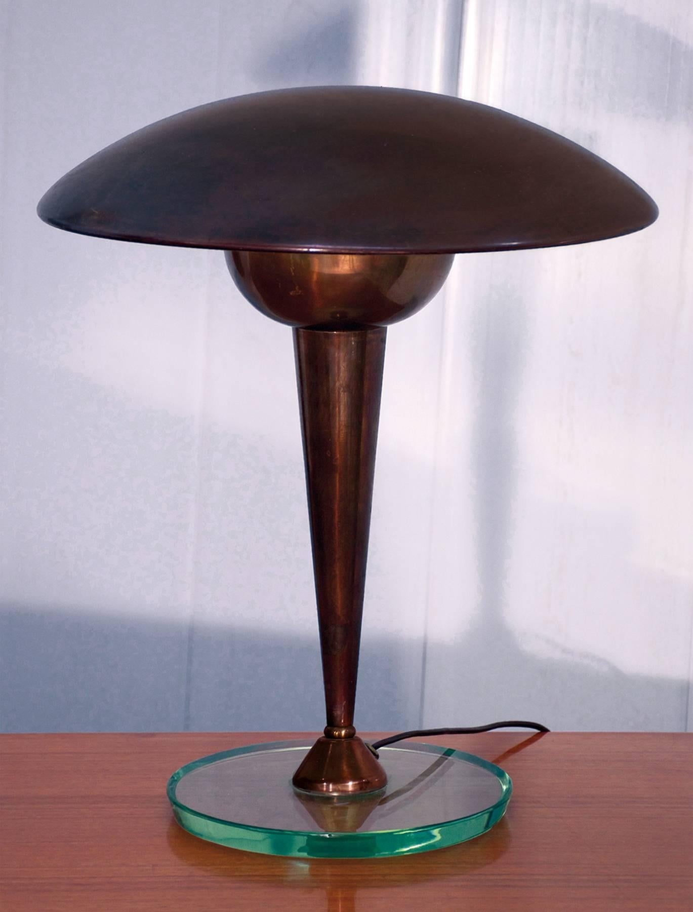 Desk lamp of the 1950s attributed to Stilnovo with brass original oxidation.
The centre column is mounted on thick bevelled round glass base (thickness 2 cm) with an adjustable pivoting lampshade.
In very good conditions of the period with beautiful