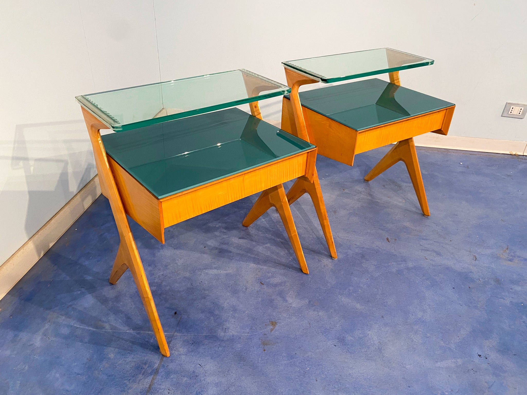 Gorgeous pair of maple nightstands designed by Vittorio e Plinio Dassi in 1950. Its uniqueness is primarily due to their original sculptural shape design on the sides, in addition to the amazing emerald green color of the glass top contrasting