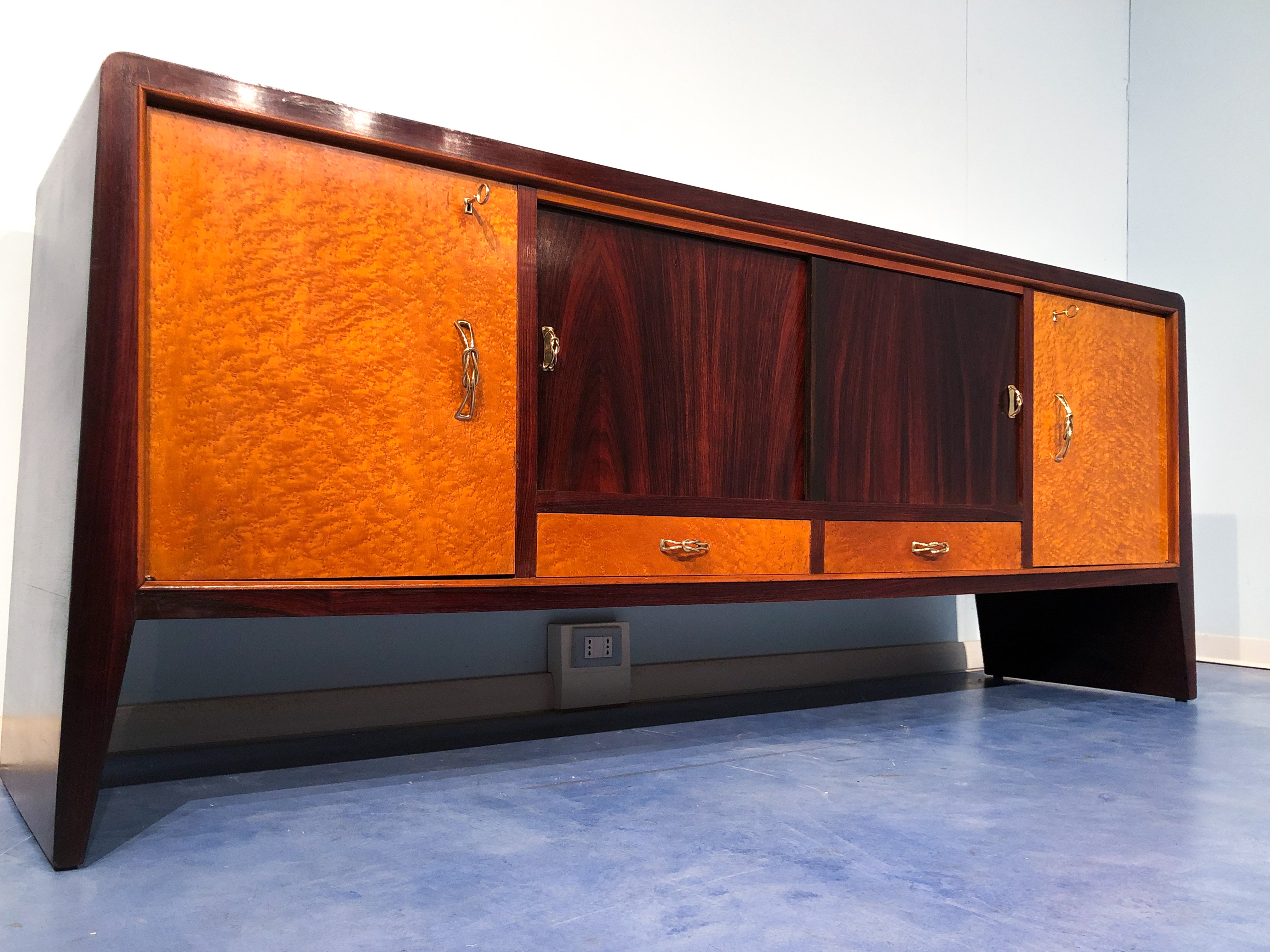 Pretty Italian mid-century  sideboard attributed to Guglielmo Ulrich, produced in the 1950s. The top and sides are made of teak on solid tapering flared legs enclosing two doors and two drawers in birdseye maple, two sliding doors in teak too. It is