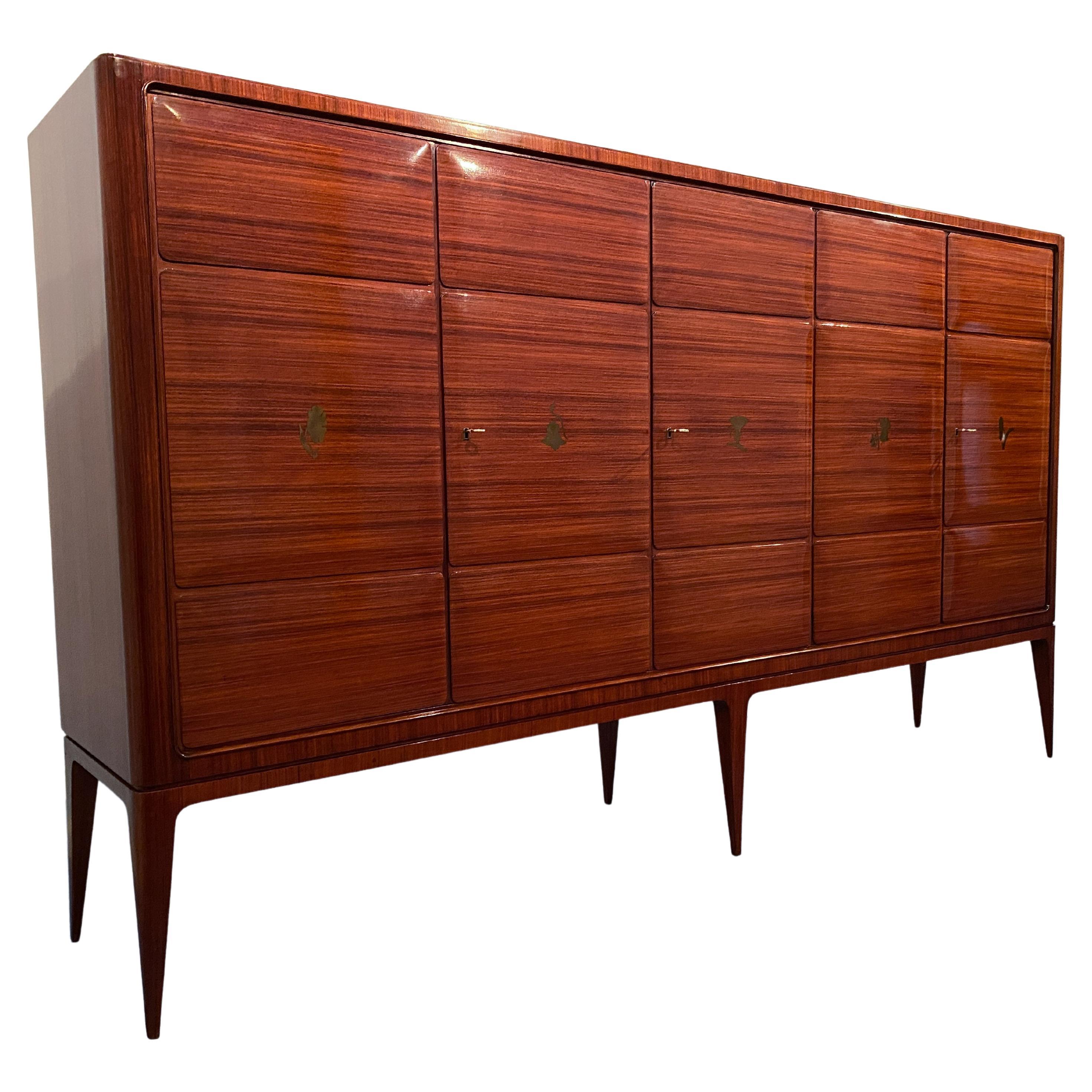 Magnificent Italian sideboard designed by Paolo Buffa in the 50s. Underlining the upper floor is wood veneer arranged in a herringbone pattern. The doors have three panels each embellished with a splendid brass inlay with floral motifs. The lower