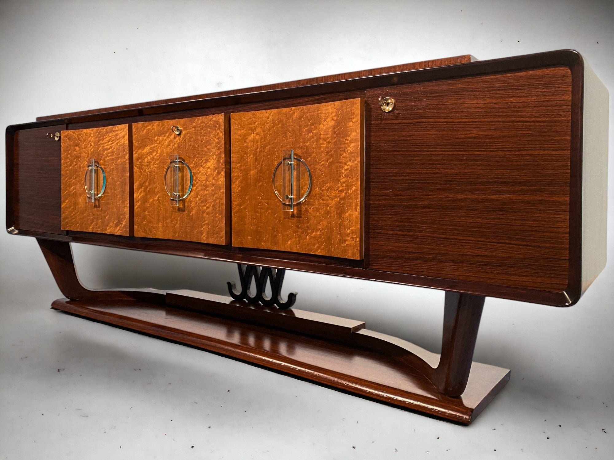Osvaldo Borsani designed this beautiful Italian sideboard in the 1940s. With its unique design and excellent manufacturing quality, the sideboard stands out from the crowd.

The glass handles on the three central doors are magnificent. The slight
