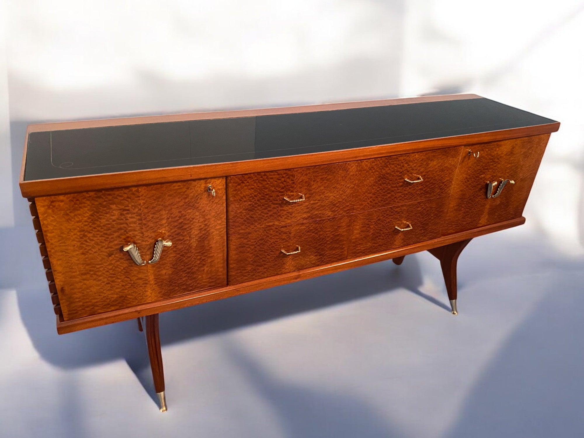 Questa credenza, disegnata da Vittorio Dassi negli anni '50, è semplicemente stupenda. È realizzato in radica di amboyna di alta qualità, caratterizzata da toni caldi che la rendono ancora più affascinante. Il piano in vetro nero con decorazione