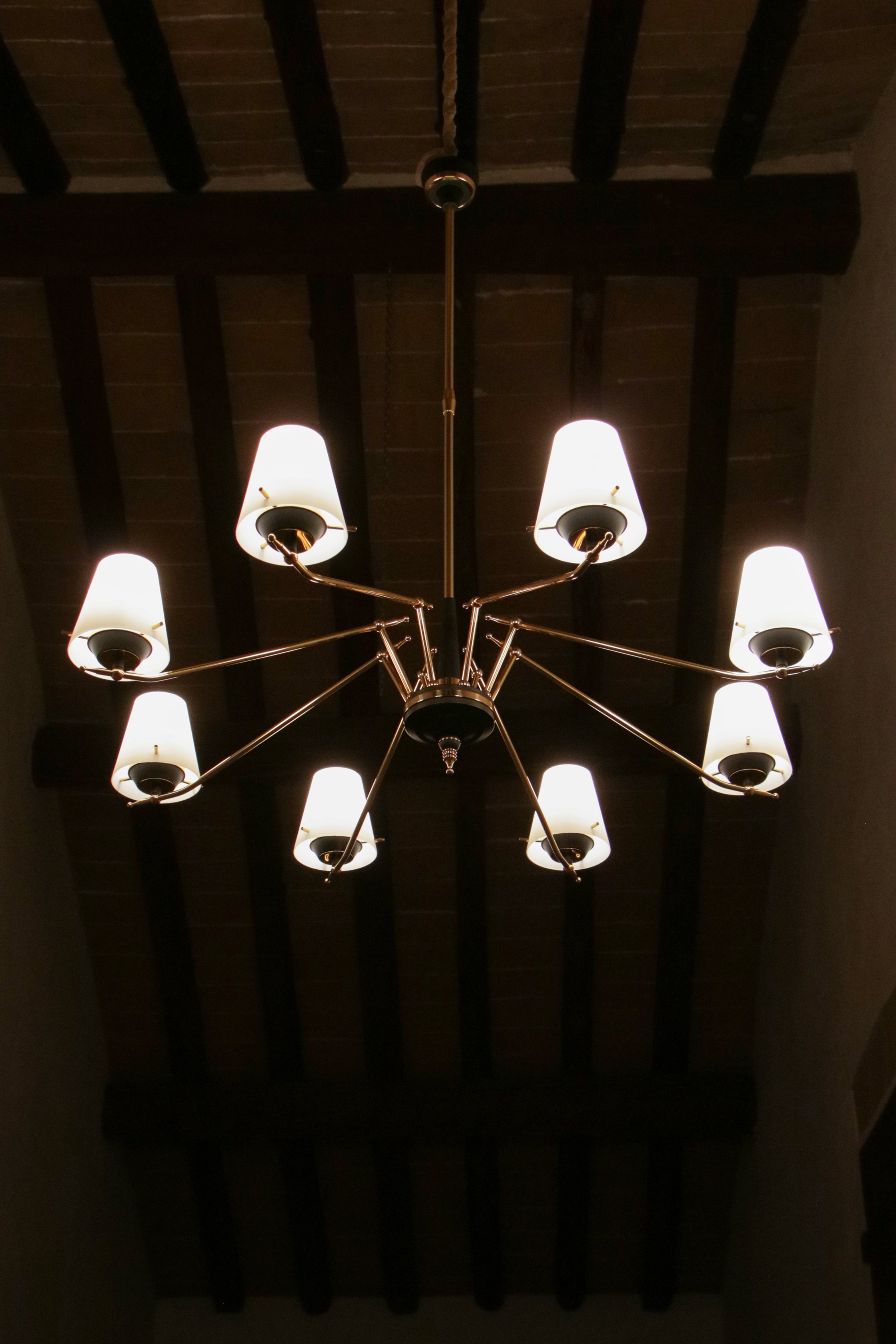 Lampadario italiano degli anni '50 attribuito a Stilnovo, realizzato in ottone lucido e alluminio laccato nero. Dispone di otto luci di formato E14. Questo lampadario elegante è stato rifinito con cura nei minimi dettagli. Si noti la parte finale