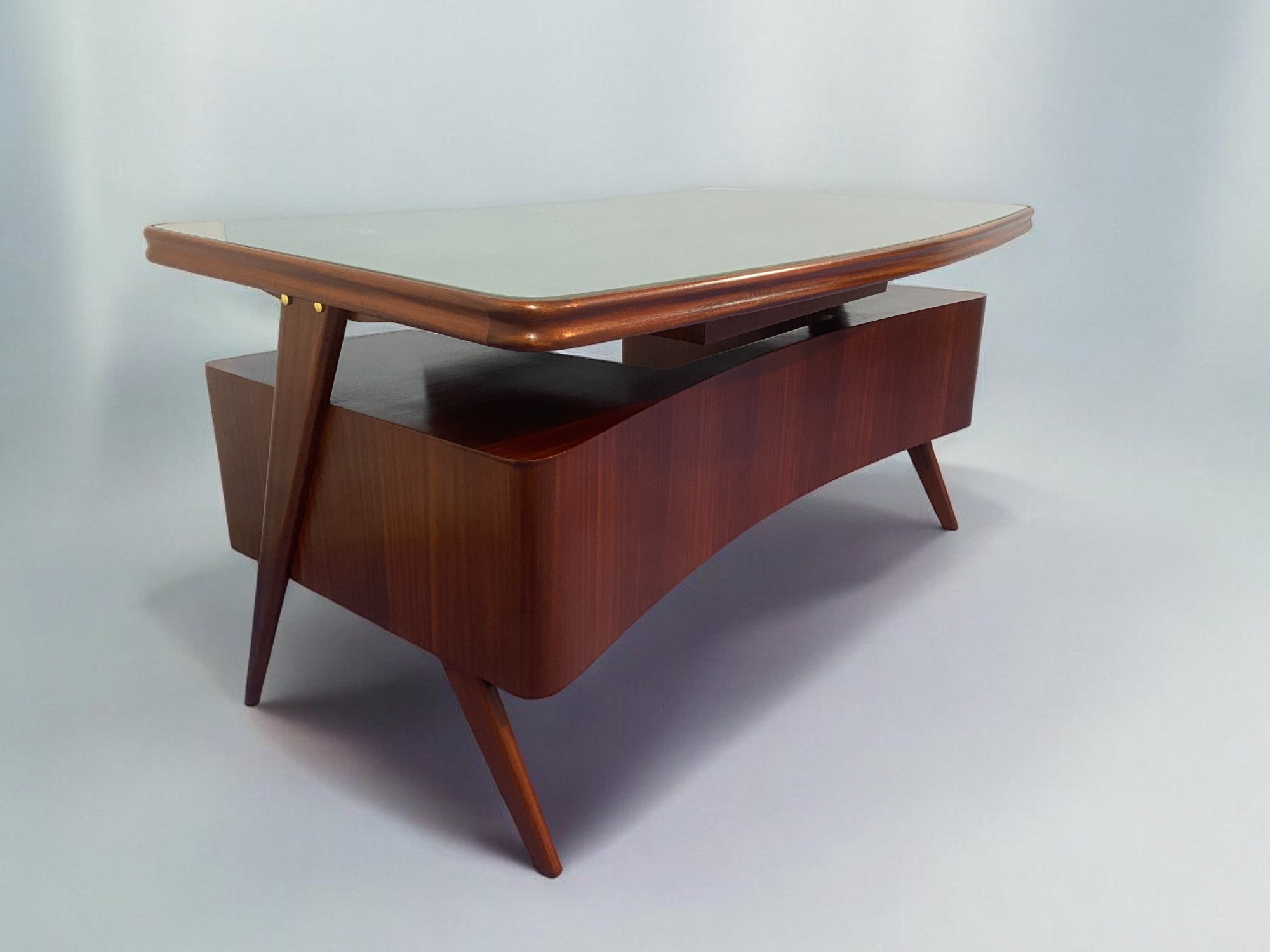 Elegante scrivania direzionale disegnata da Vittorio Dassi negli anni '50, design davvero unico caratterizzato da un piano sinuoso con una linea ad arco in contrasto con la parte centrale convessa nella direzione opposta, raffinati piedini a spillo,