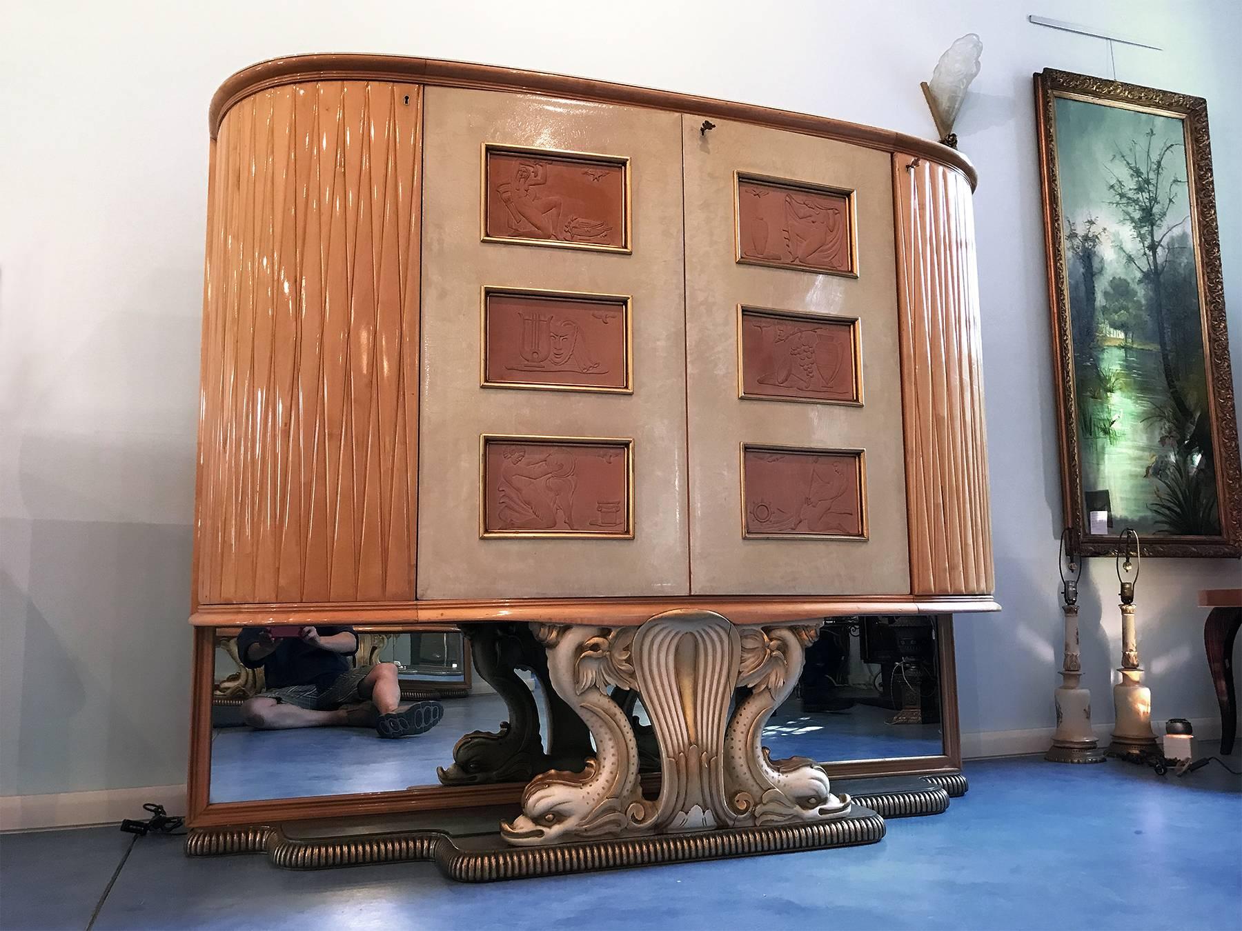Spectacular wet bar cabinet in maple and parchment design attributed to Osvaldo Borsani in the 1940s.
On the parchment doors, there are wood sculptured figures of stylized women, luxury insides in maple that light up when opening the doors, glass