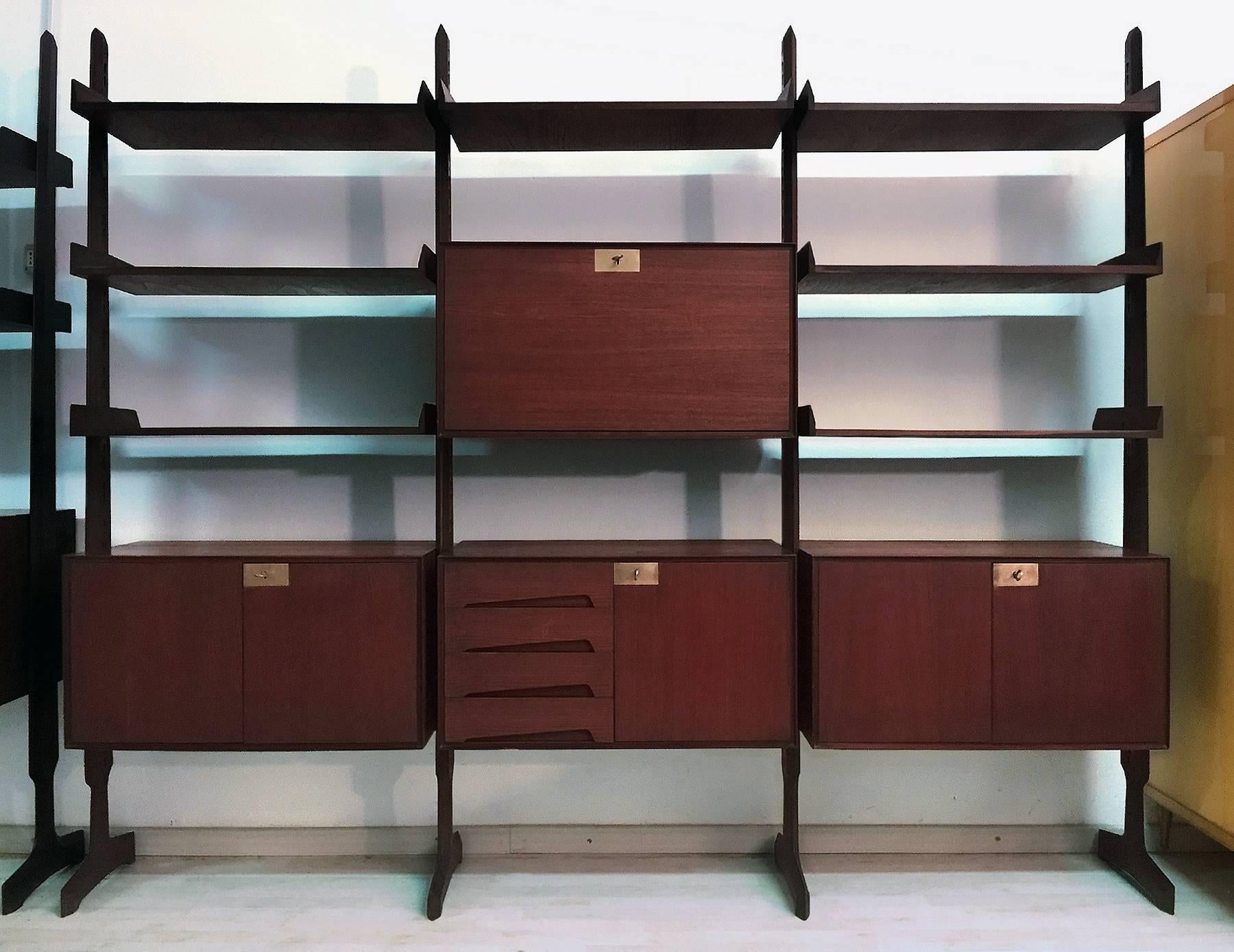 This bookcase is composed by three modules freestanding, suitable to be moving and placed at will in the home, equipped with seven shelves, one central cabinet with drop-leaf door available as secretaire, two cabinets with two doors and one cabinet