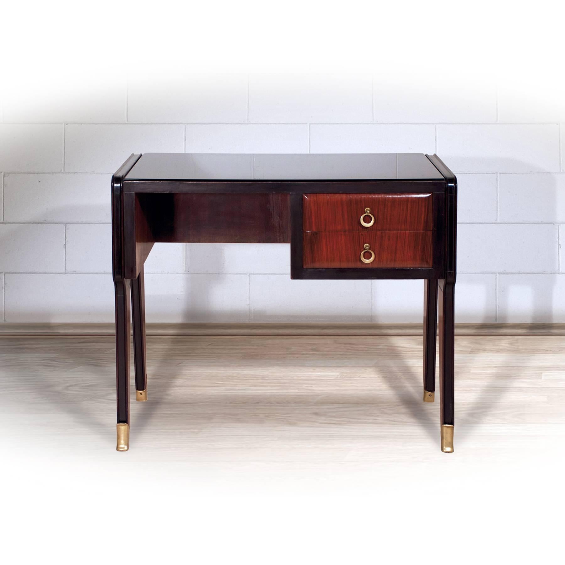 A small rosewood writing desk designed by Vittorio Dassi in the 1950s, with dusky black glass top, two drawers with brass ring handles and feet with brass sabots.
It's in excellent condition of the period, recently restored and ready to use.
The