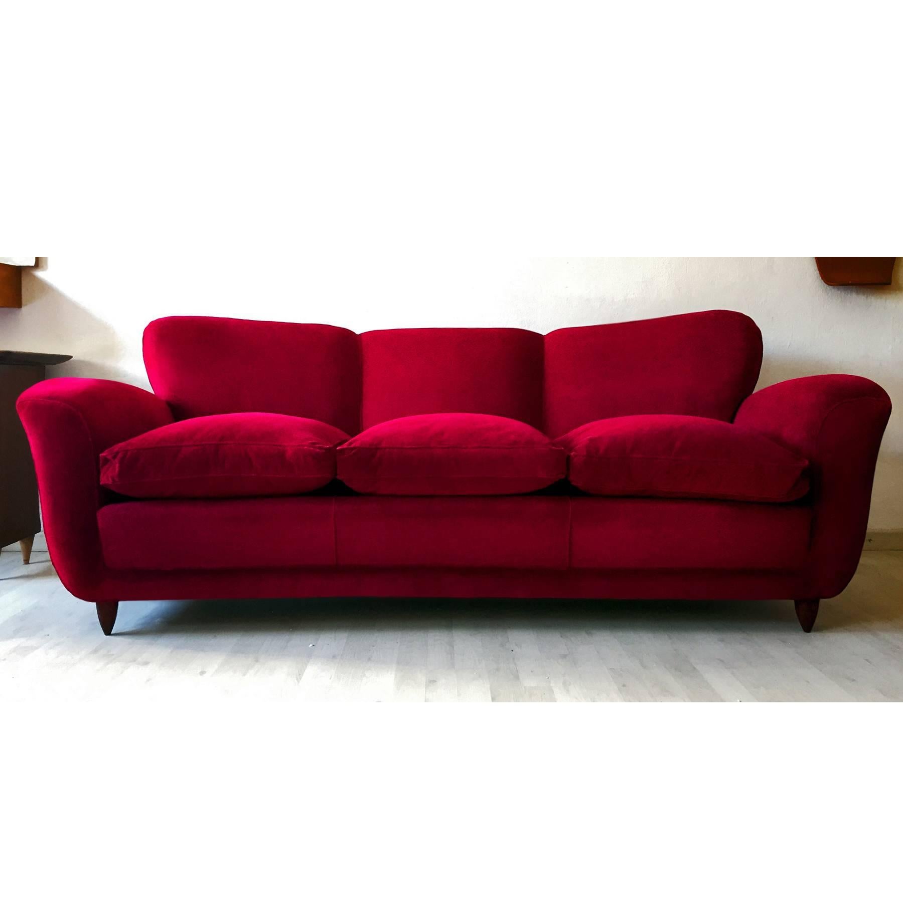 Very stylish and extremely comfortable Italian sofa three-seat with winged backs, design attributable to Guglielmo Ulrich in the 1950s.
It's upholstered in a gorgeous deep scarlet red velvet, original of the period and preserved in excellent