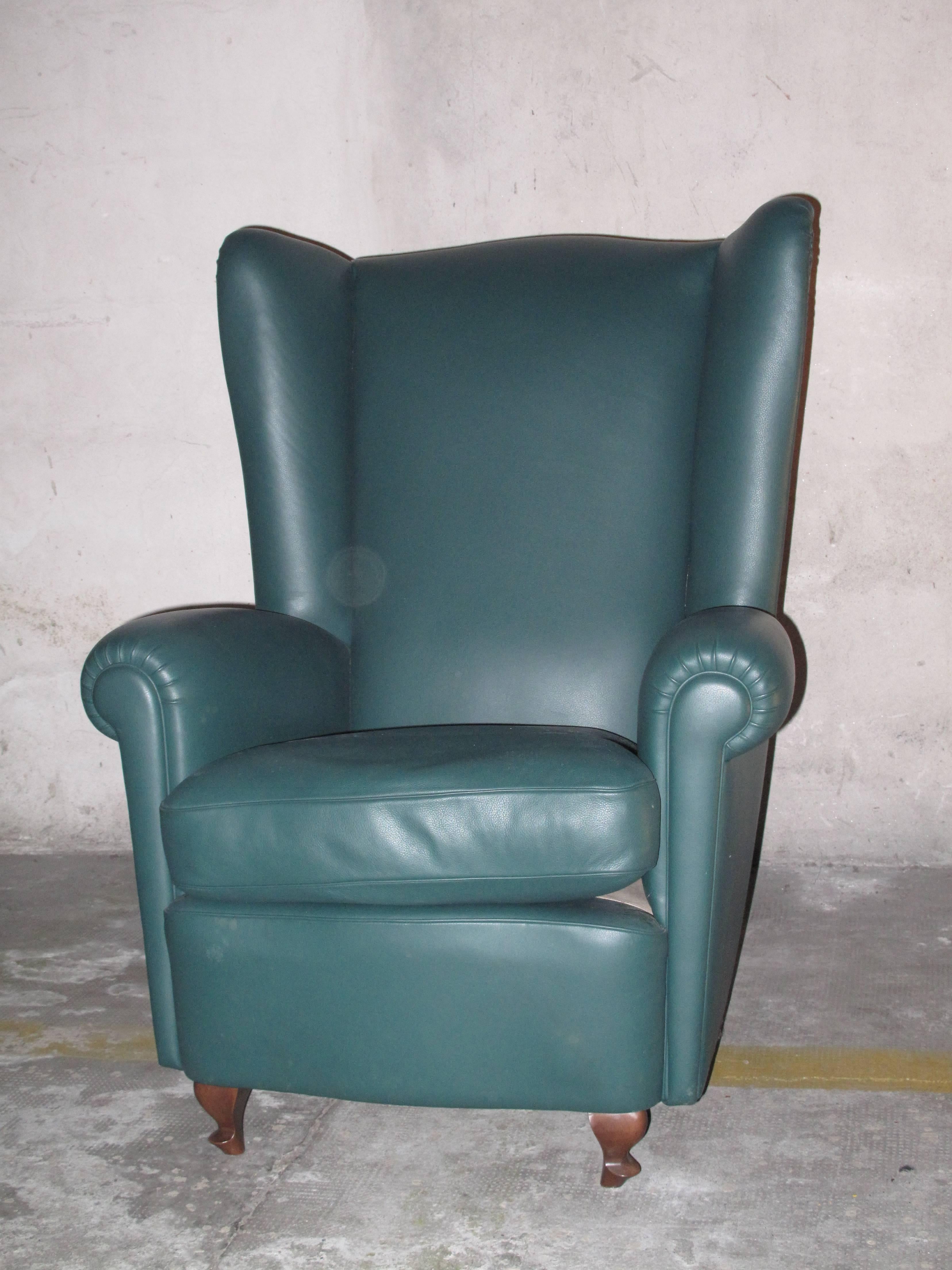 Striking high backed, leather armchair with rolled arms and slight wingtips at the top of the back. Leather wrapped tacks. Sculpted wood legs.