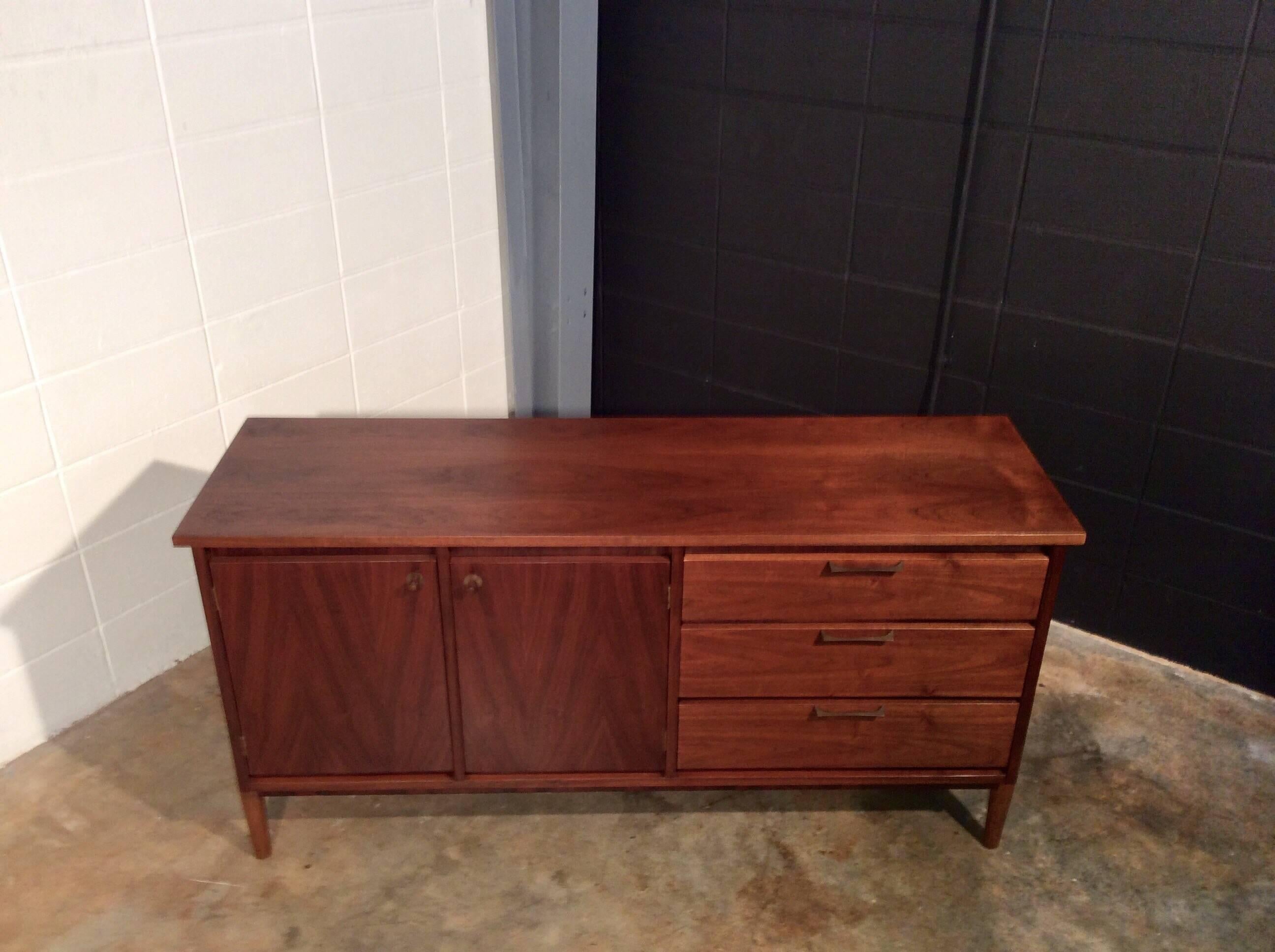 Unique Mid-Century Modern Credenza or Buffet. This credenza is a well-built piece from Stanley Furniture's Distinctive collection. It features warm walnut wood and external legs to create a more distinct appearance. This item has been restored and