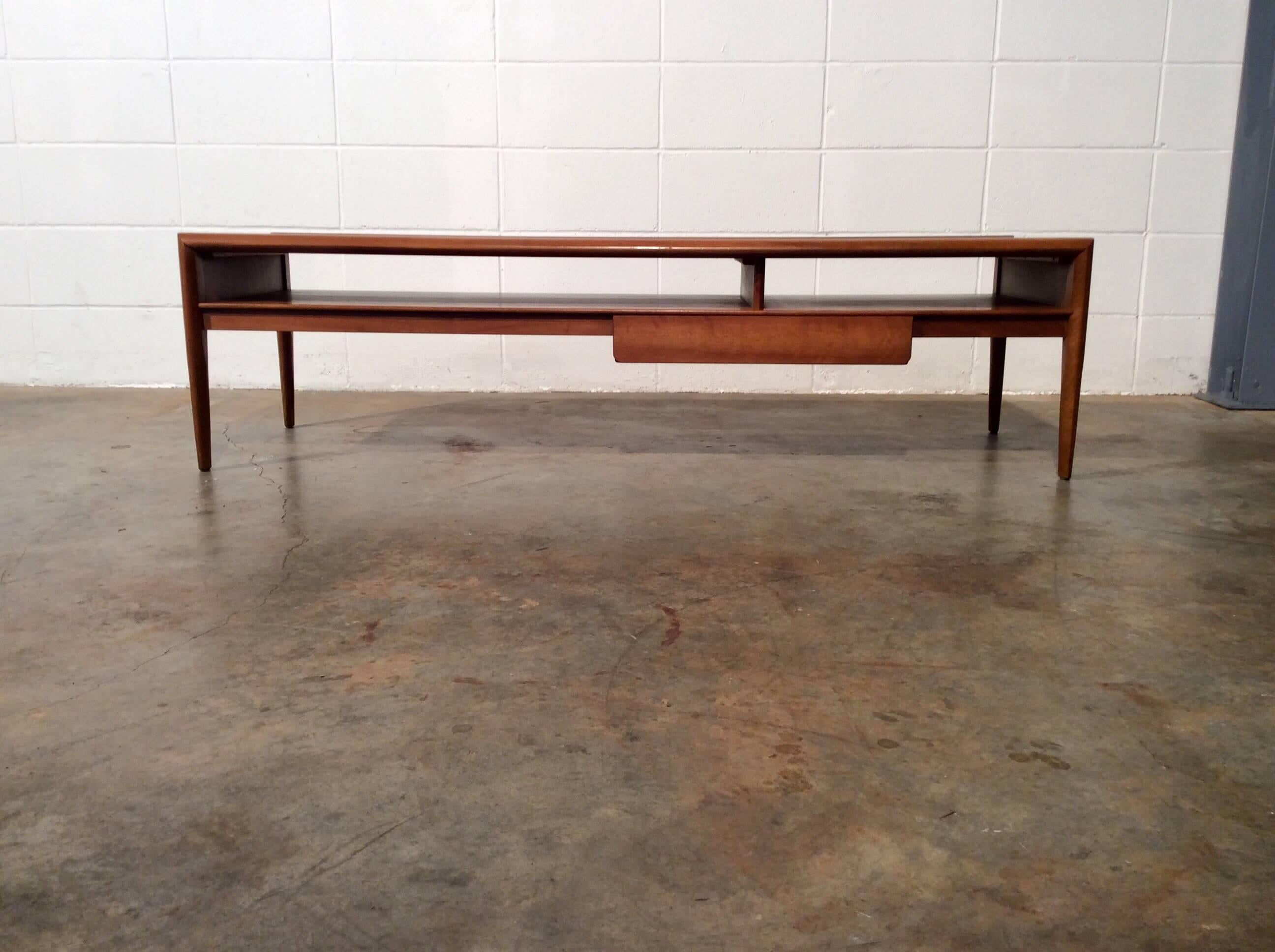 Mid-Century Modern Drexel parallel walnut coffee table by Barney Flagg.
Rarely seen long Walnut coffee table with a drawer and slotted storage. Table has had a glass protecting the top it's entire life. No defects that would detract from value or