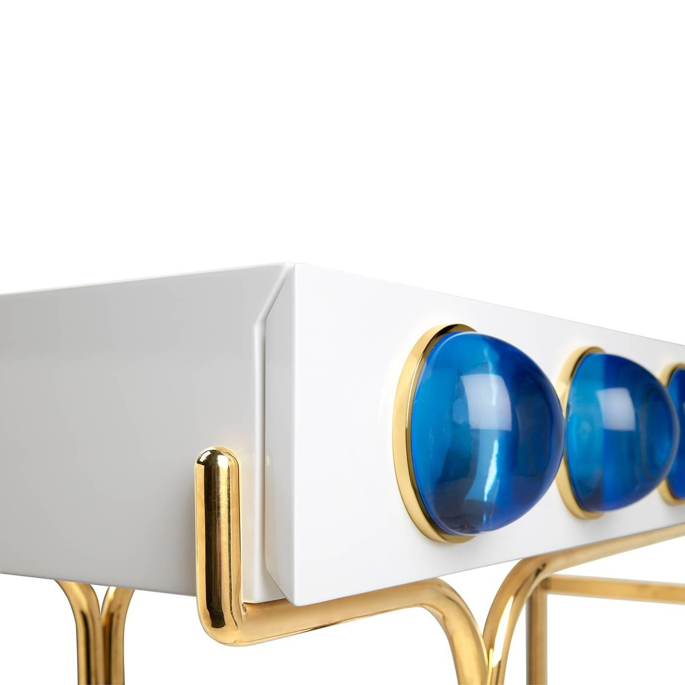 Futuristic elegance. A glossy, white lacquer cabinet cradled by a sinuous brass framework and capped with blue solid acrylic cabochons. Small footprint but big impact, our Globo console is guaranteed to deliver mega glamour.

Specs:
White,