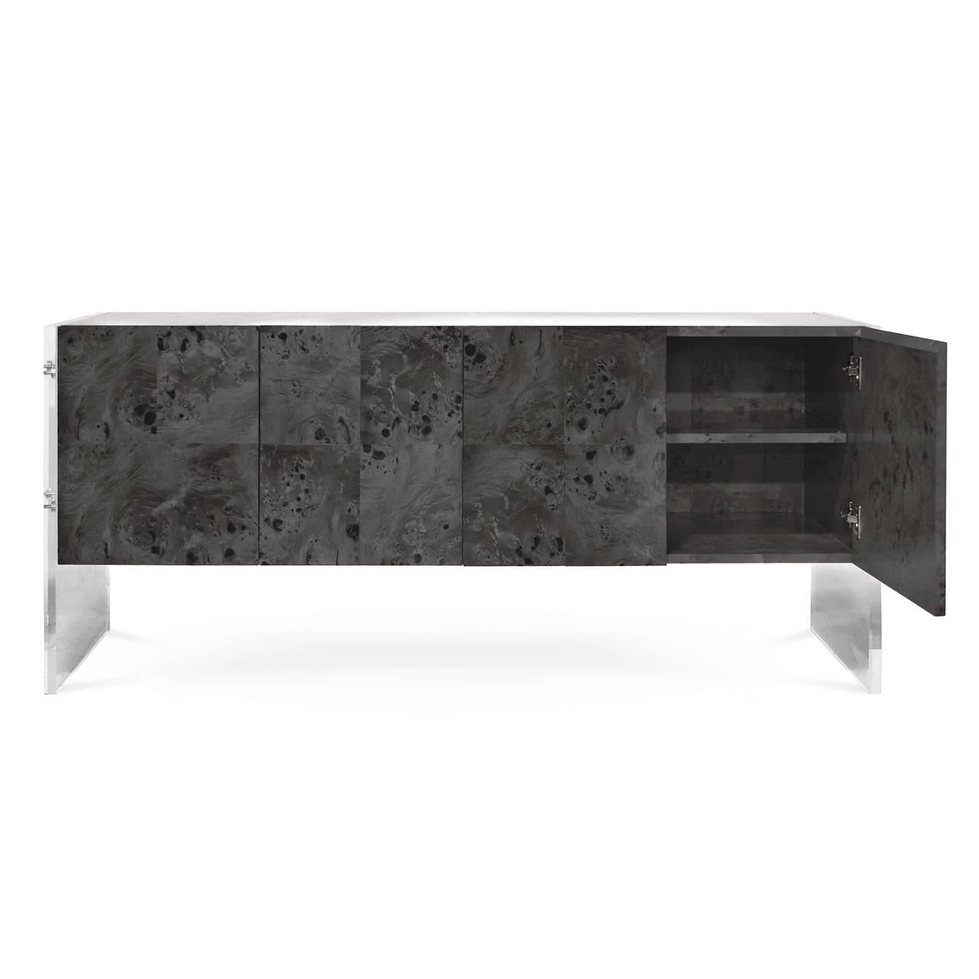 Timelessly chic. A Minimalist world of burled wood, Lucite, and stainless steel. Pieced lindera wood floats between Lucite legs with stainless steel accents. Pieced veneer cabinet faces showcase naturally occurring patterns in the wood, and an