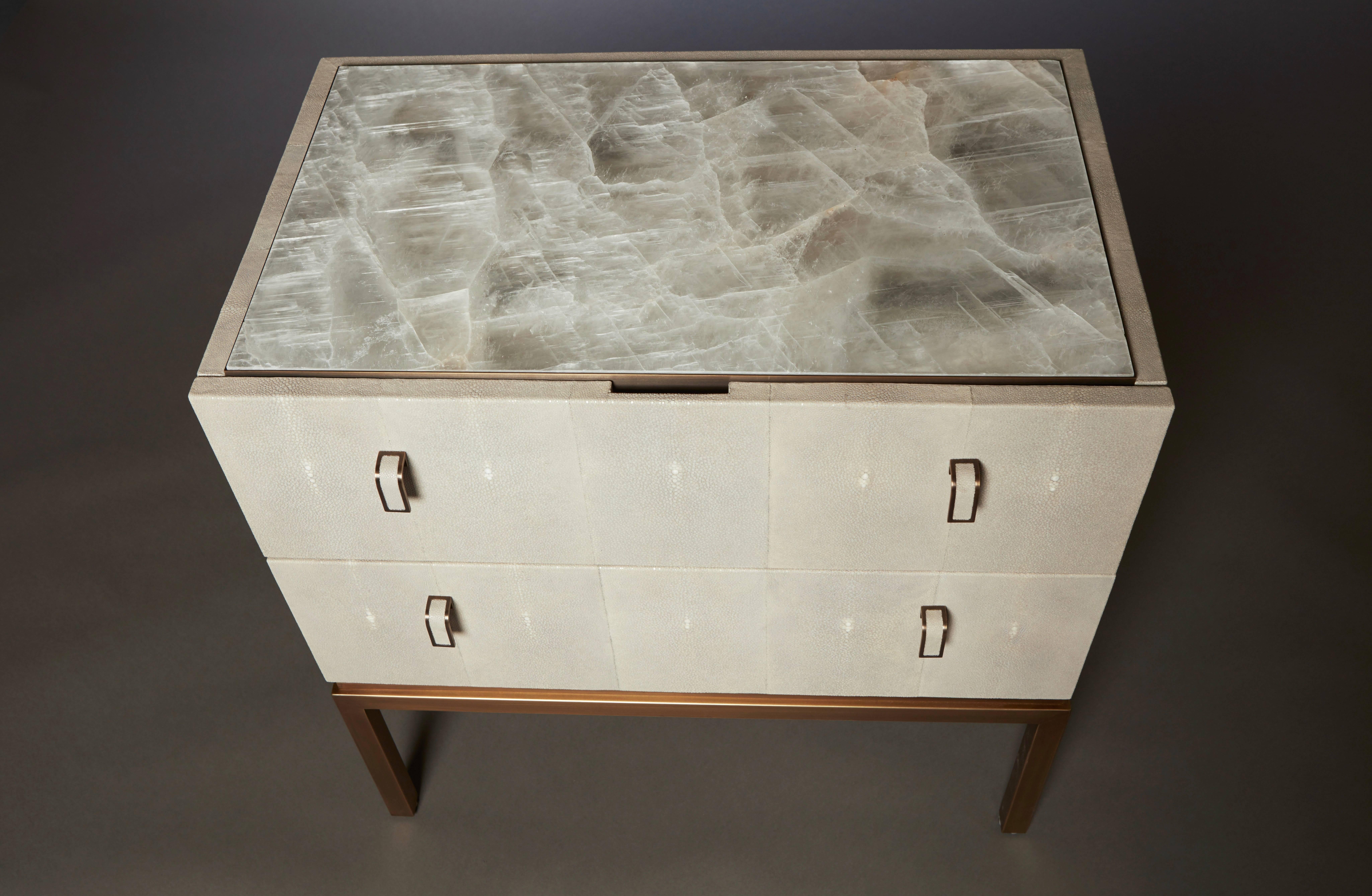 The Water nightstands feature two hand-dyed shagreen drawers with lacquered solid oak interiors sitting atop a decorative patinated bronze edge band. Chosen for its alchemical and healing properties, the translucent selenite tabletop is associated