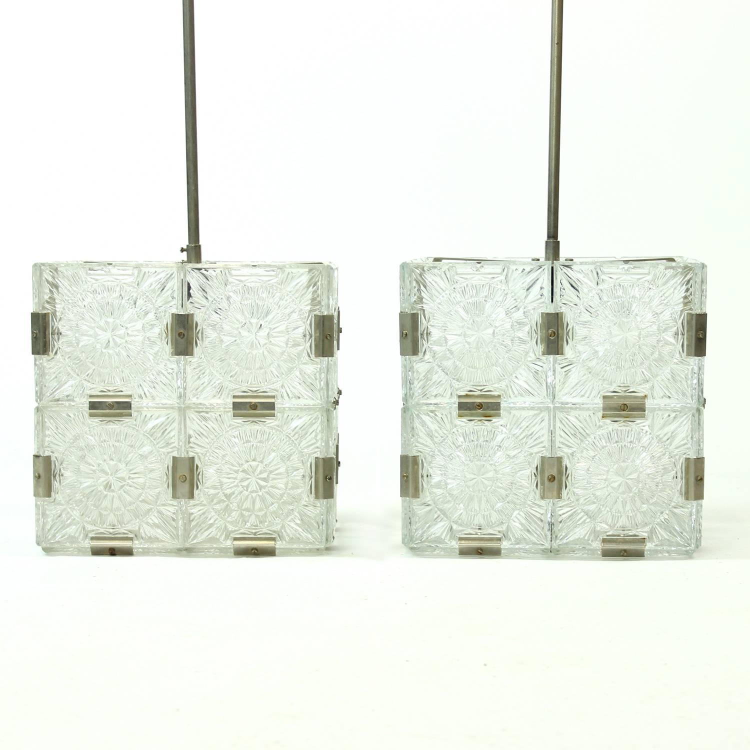 These are two beautiful glass pendants produced by Kamenický Šenov in 1970s. The light is hanging on a chrome metal construction. The light is made of square glass panels combined to make a glass cube. Beautiful design and light. Each panel is made