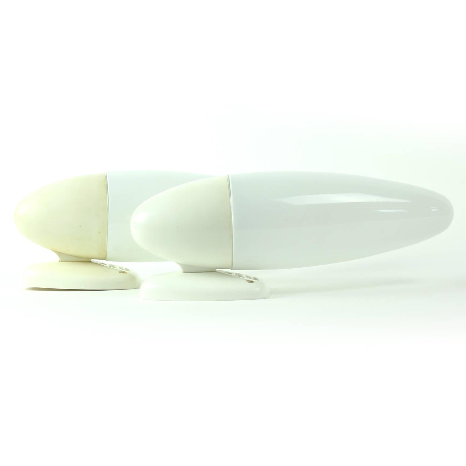Two all white wall lamps in style of the famous Brusselles era of early 1960. Made in Czechoslovakia, the home design leader at the time. Beautiful, stylish and futuristic shape of the lamp. Shield in white opaline glass screws onto the white