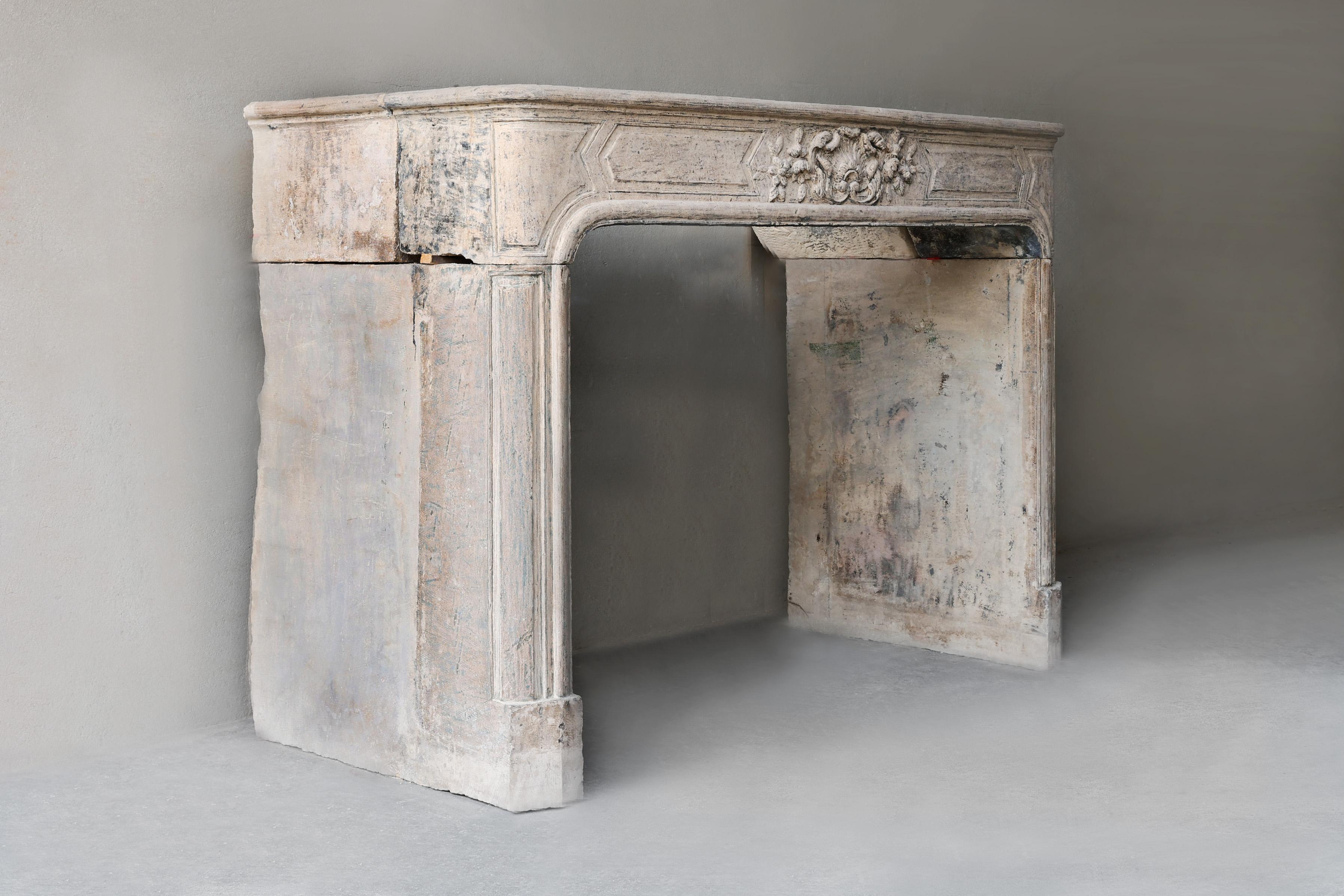 Beautiful timeless antique fireplace with lots of elegance made of authentic French limestone from the 19th century. This fireplace in Louis XIV style has refined details and a beautiful patina, which makes the look even more authentic. The round