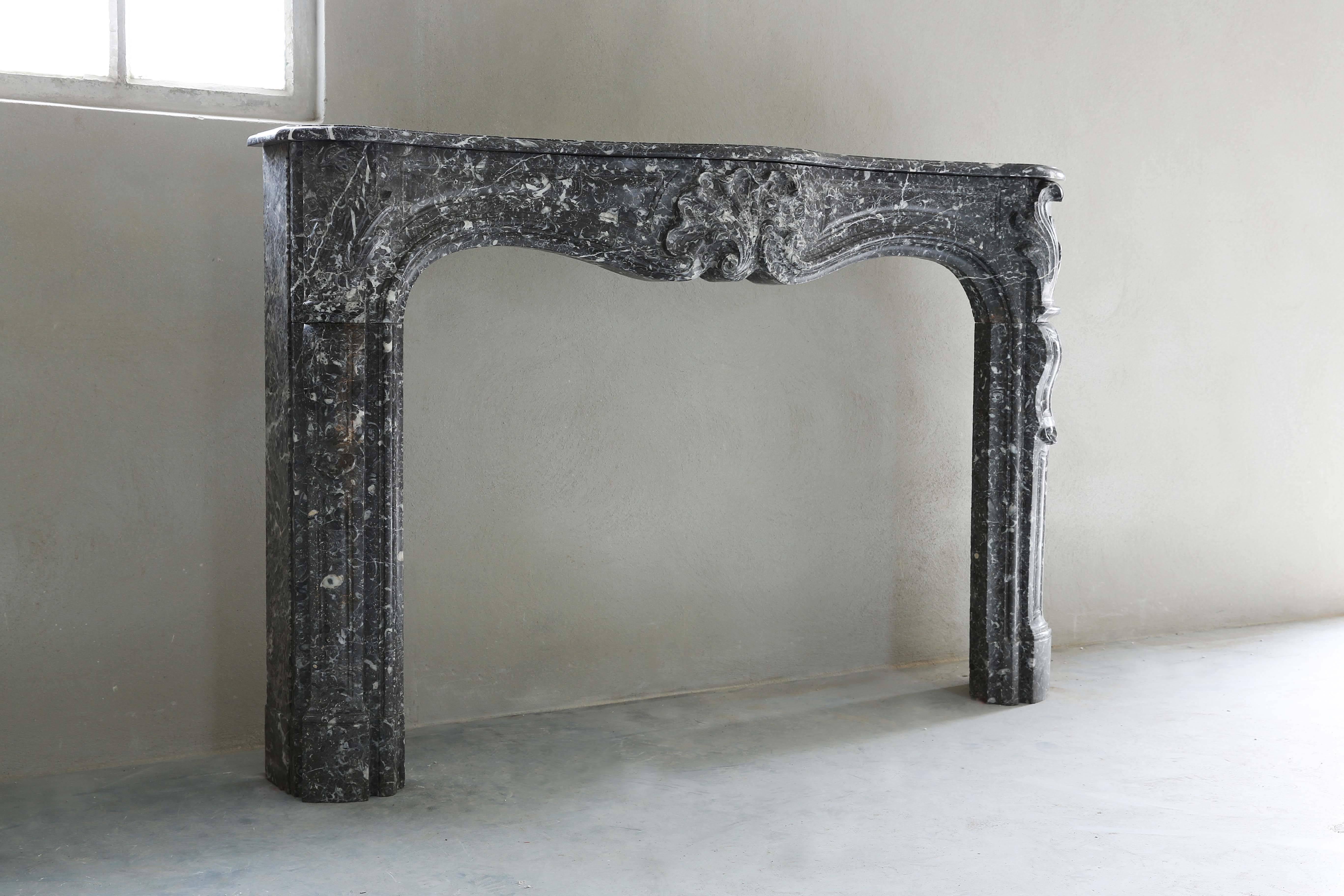 A decorating and charming antique fireplace with nice coquilles in the style of Louis XV. The kind of marble is Gris de Ardennes and comes from Belgium.