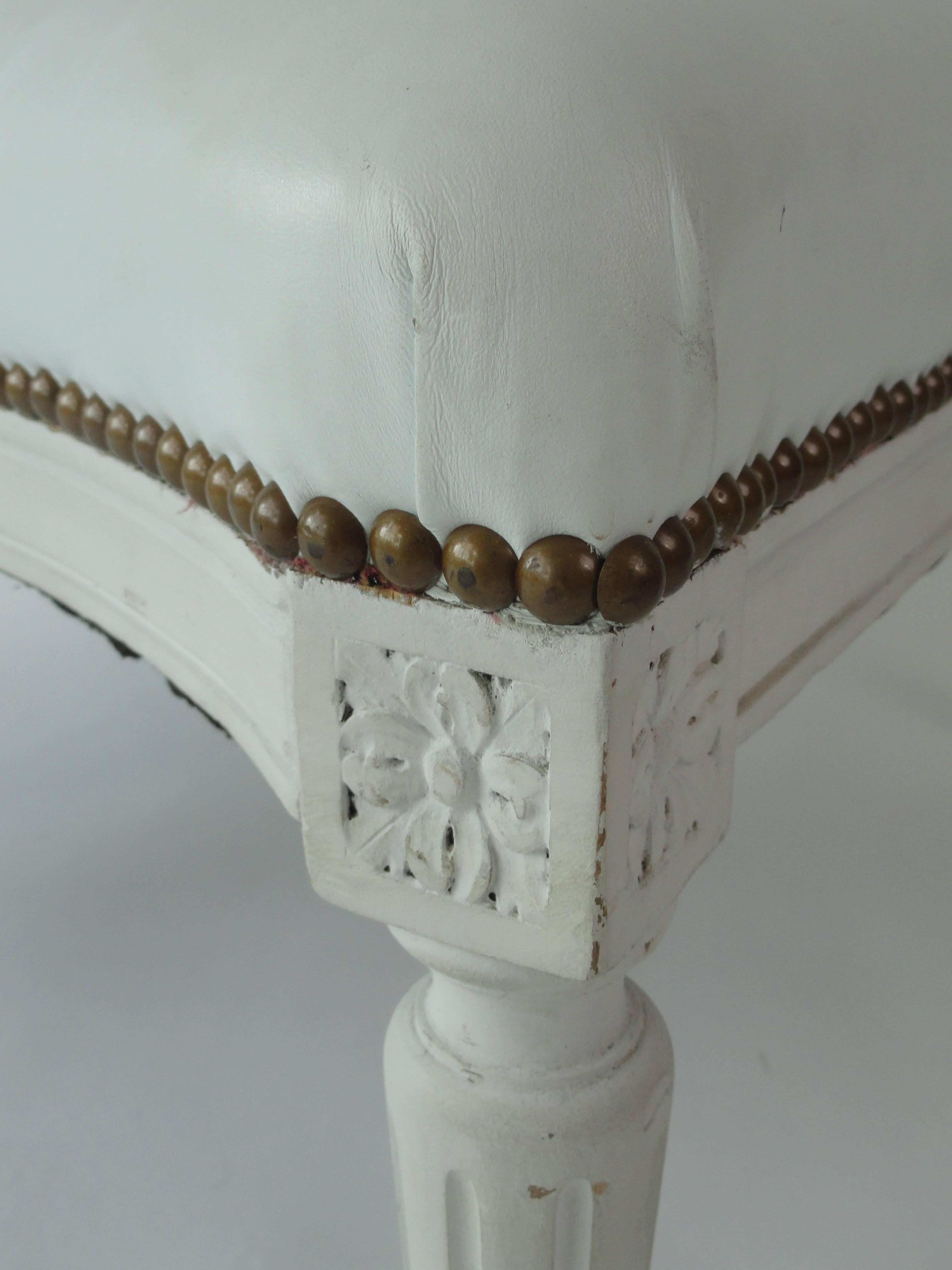 Louis XVI style bench made of carved wood and covered in white leather with brass nailheads.