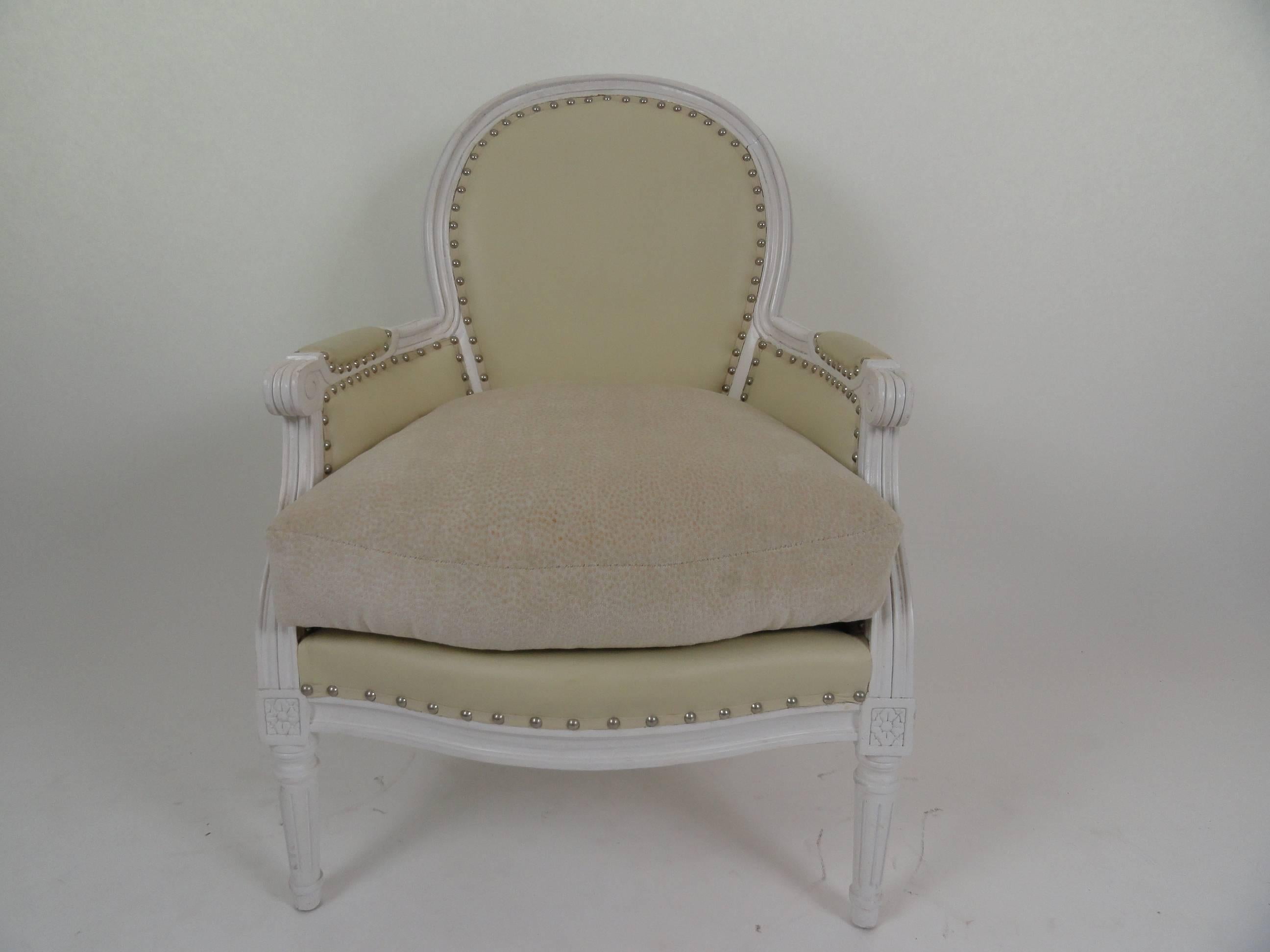 Louis XVI style bergere with white painted wood and nickel nailheads. Upholstered in leather. Seat cushion upholstered in cotton.