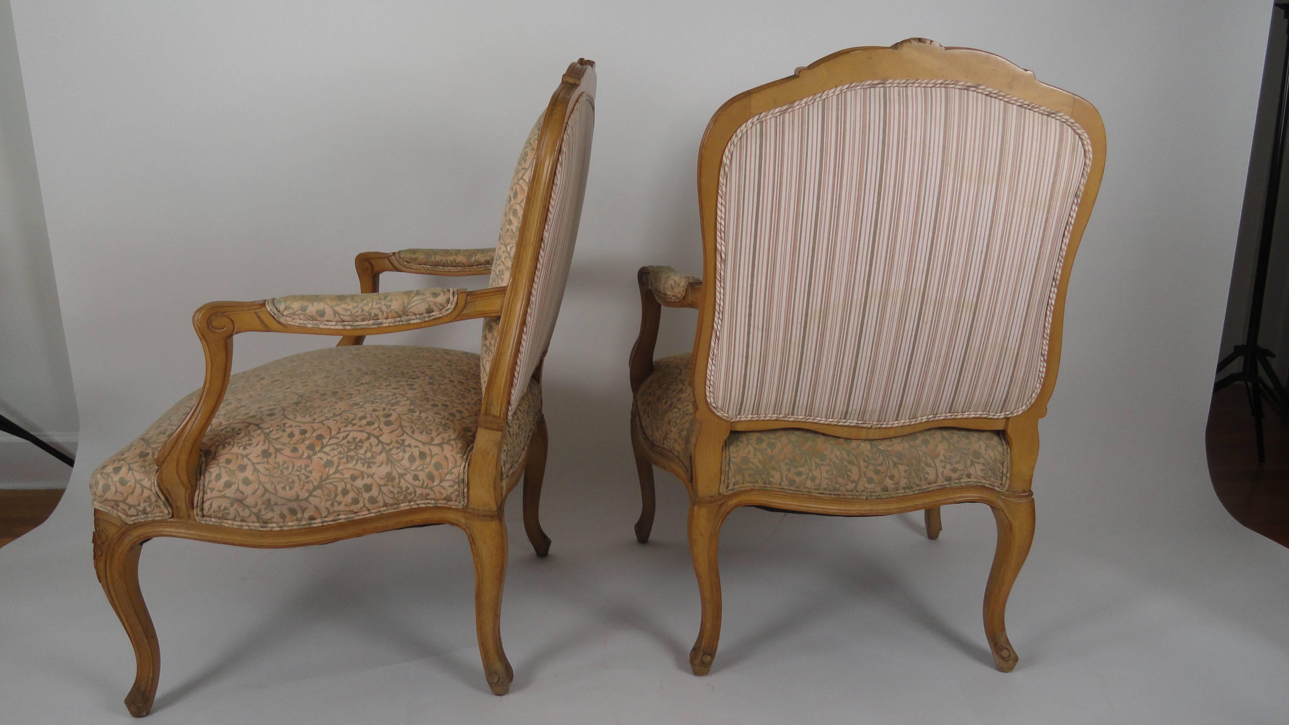 Pair of French open armchairs in the French Louis XV style. Cartouche shaped padded backs, padded down scrolled arms. Serpentine upholstered seats with a curved detail on cabriole legs. Beautiful hand carving. Covered in Fortuny.
   
