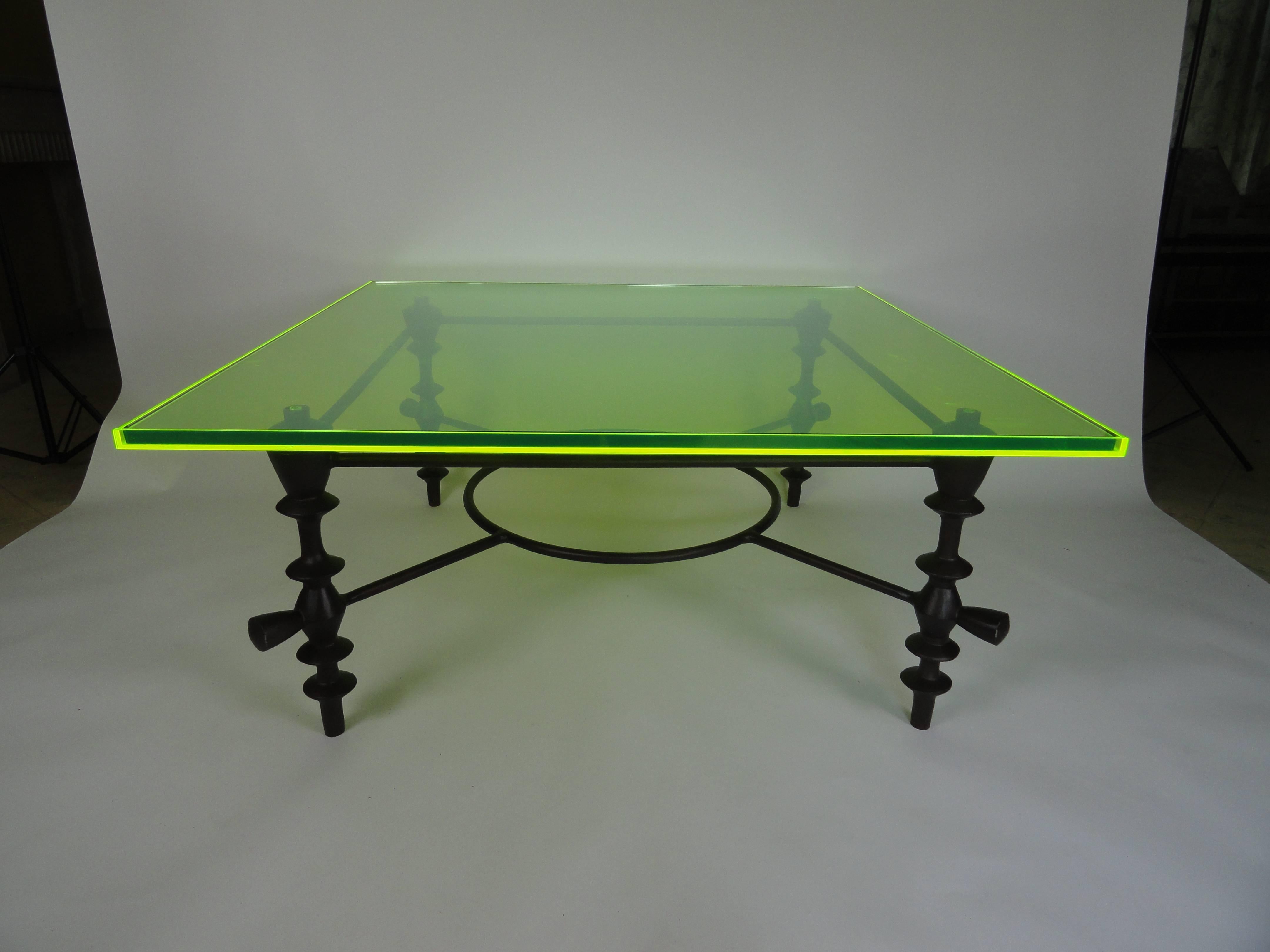 Giacometti style coffee table made of metal with a custom green acrylic top. The edges of the top absorb and refract any light which makes them appear to glow bright green. You can see it even with dim light. The acrylic tray top holds a thick piece