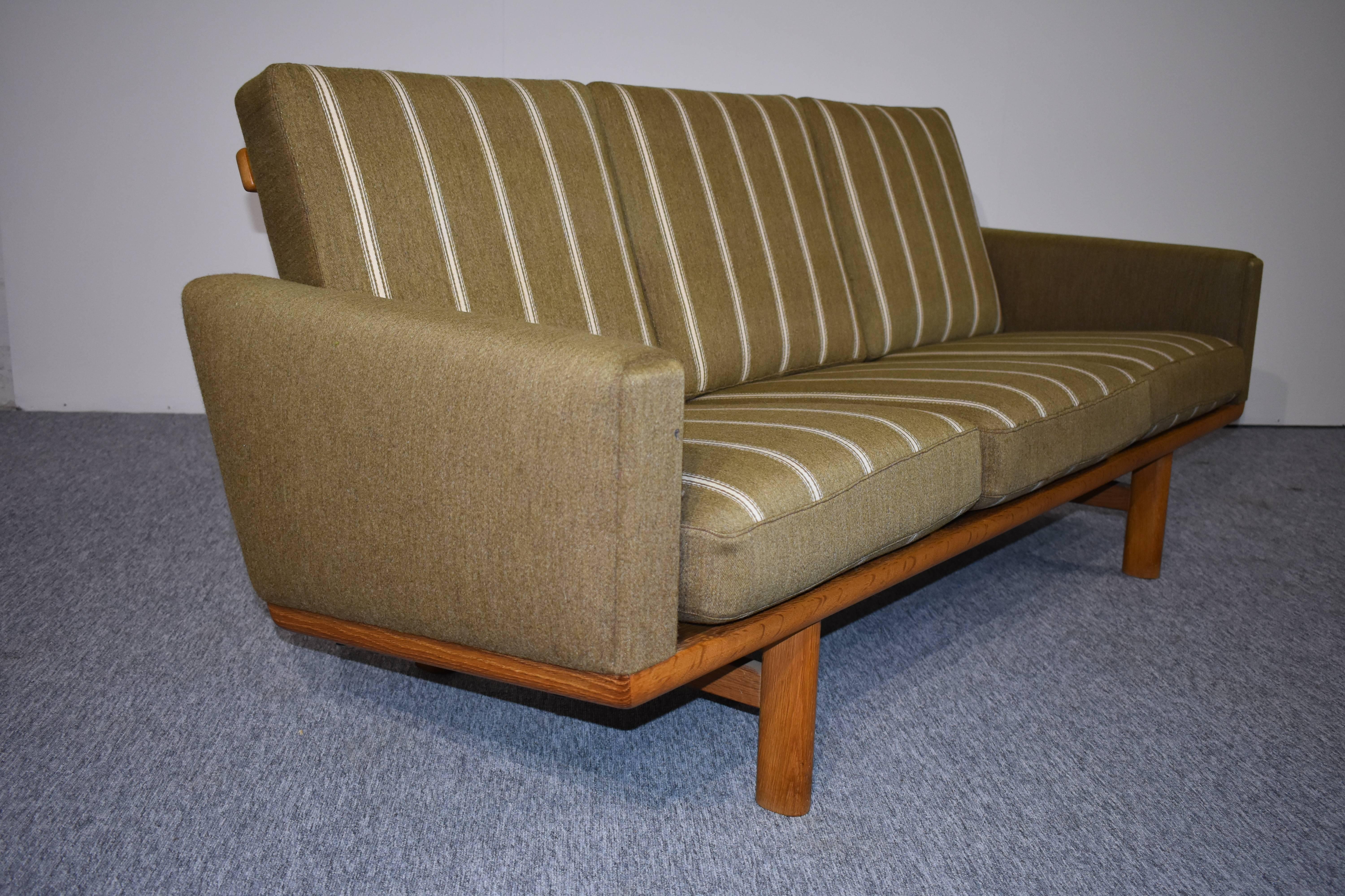 A beautiful sofa designed by Hans Jørgen Wegner for GETAMA Gedsted, the sofa is made in oak, with retro upholstery. This sofa was Wegner's most popular sofa design, because of its linear and Minimalist design. The sofa looks beautiful from all