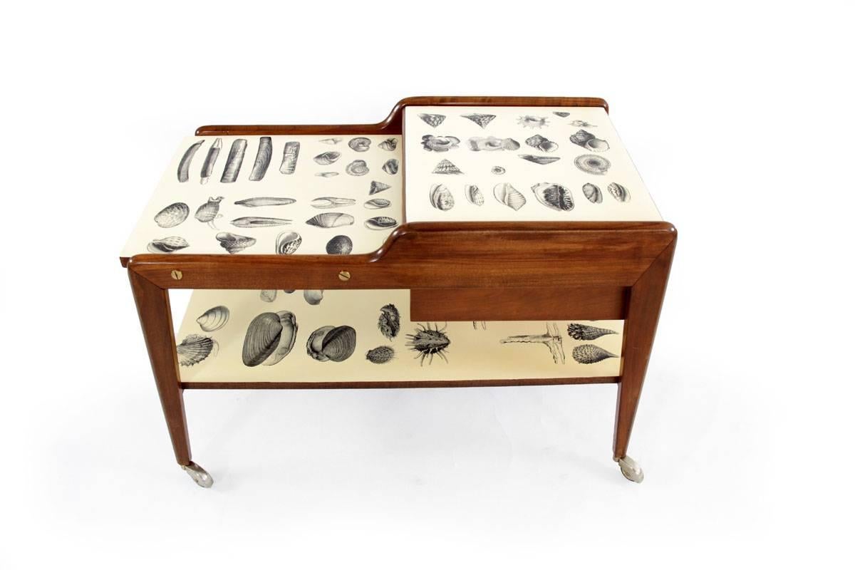 Tea Cart from Italy, 1950s in the manner of Piero Fornasetti. This Tea Cart is made of wood and has a shelf which shows shell motives as well as the tabletop. This piece is part of a complete living room set with shell motives. 

Feel free to
