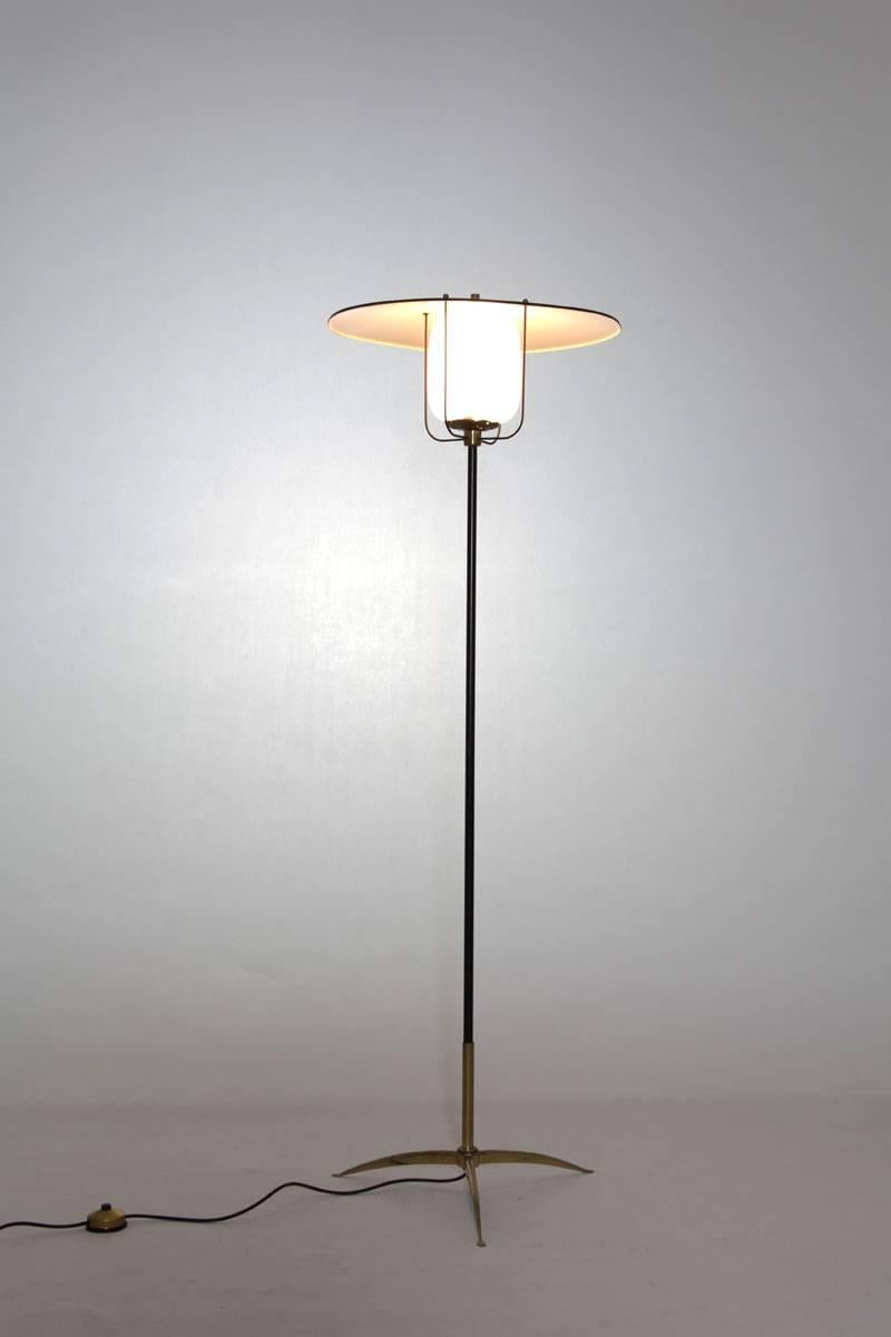 Charmante représentation du design italien des années 1950, ce lampadaire prend la forme d'une lanterne. Crafted with opaline glass, aluminum, lacquered metal bar, and brass feet, it exudes a unique blend of elegance and vintage allure. Pour une