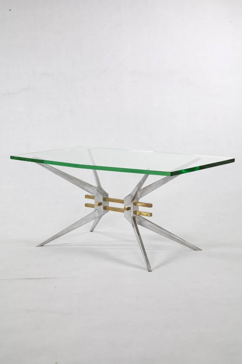 This Italian coffee table was manufactured in the 1960s. The striking aluminium table frame is a sturdy base for the heavy glass top. Two brass struts connect the tapered table legs to form an X- shaped frame. The possibility of disassembling the