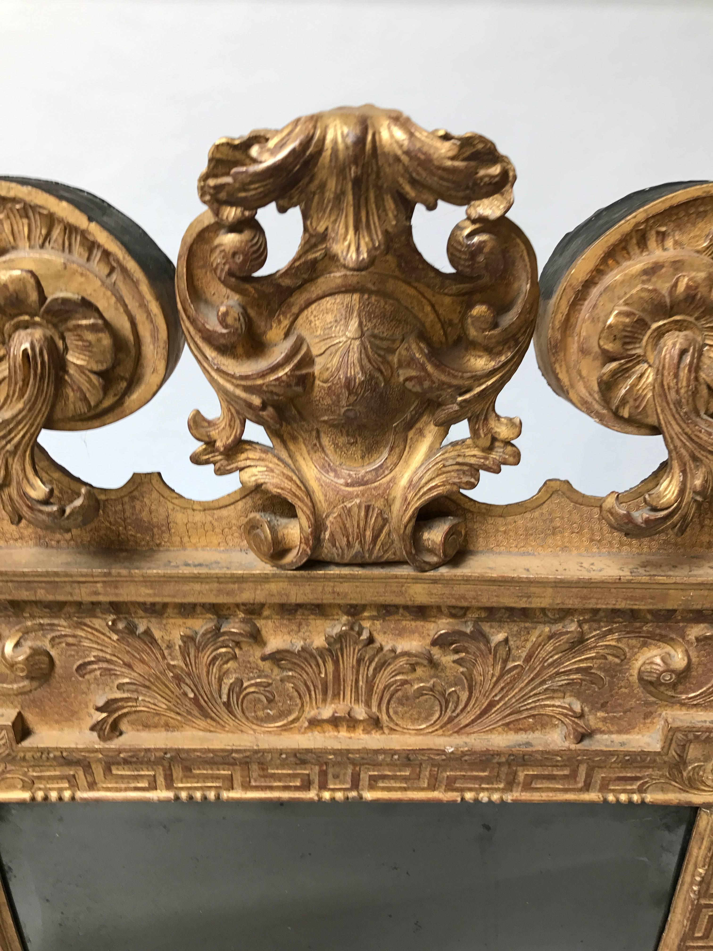 A rare and outstanding period English George II giltwood palladian mirror with period beveled glass and minor gilt restoration, crowned with a spectacular broken pediment, adorned with carved acanthus leaves, Greek key decoration and sides with