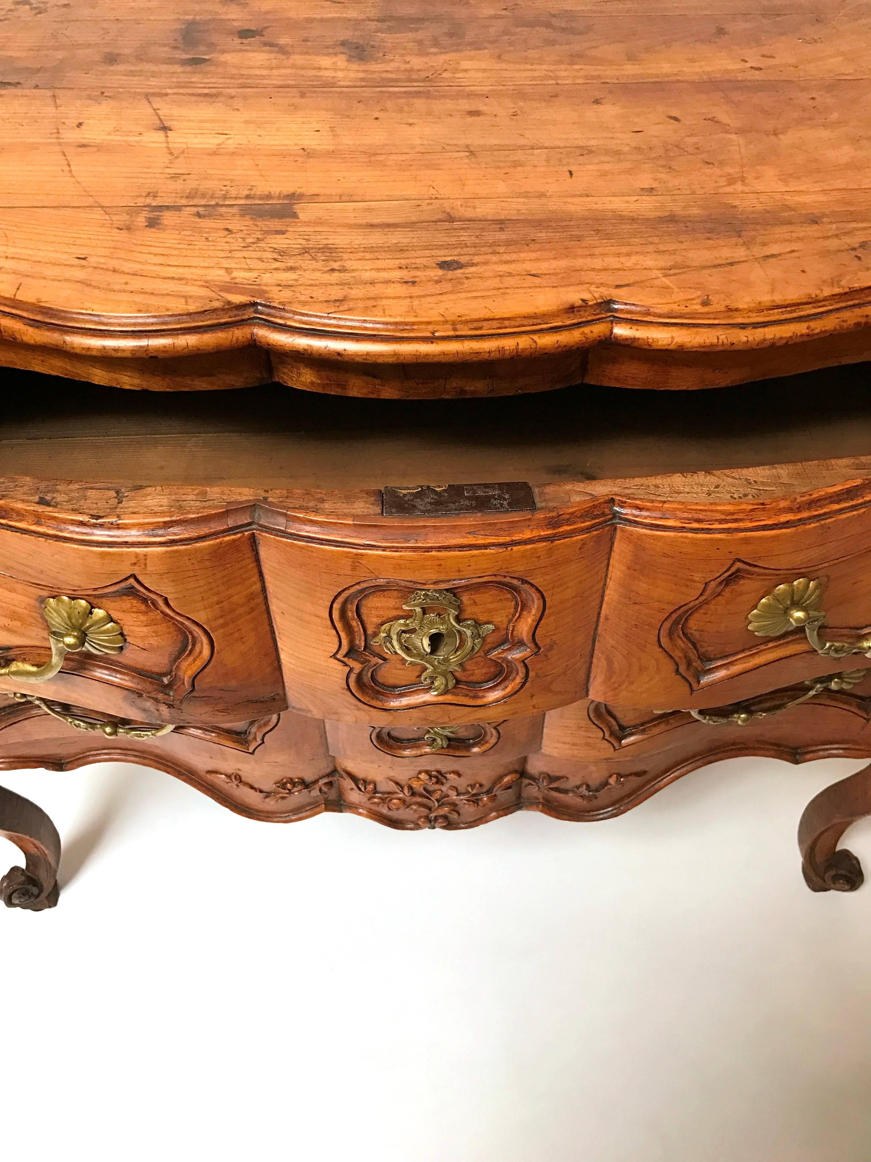 Lovely period Regence cherrywood two-drawer commode with exuberant cabriole legs and a serpentine front with original hardware from Normandy, circa 1720.
