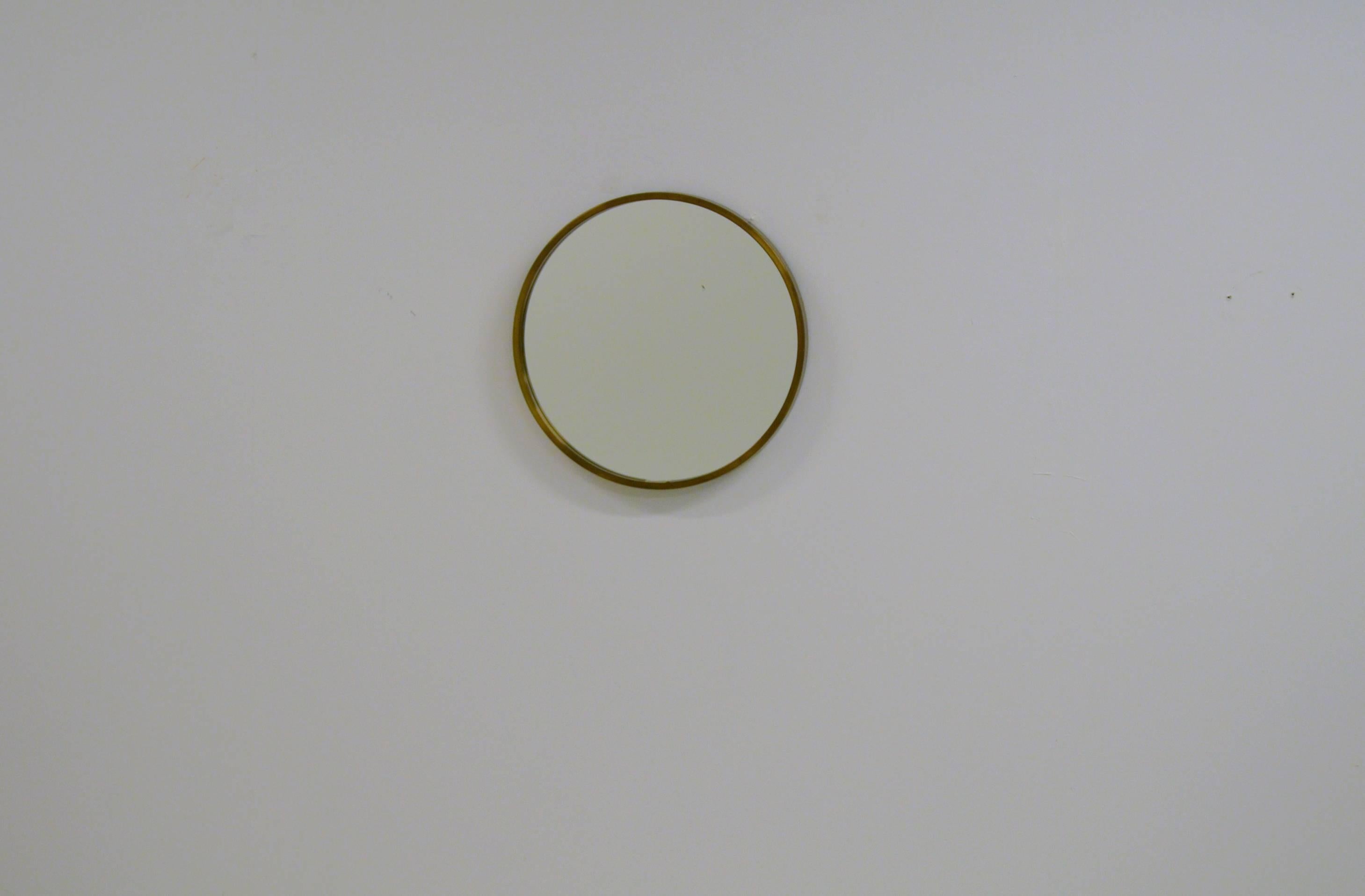 Round glass mirror from Glasmäster with brass frame. The glass has one permanent black spot in the glass.