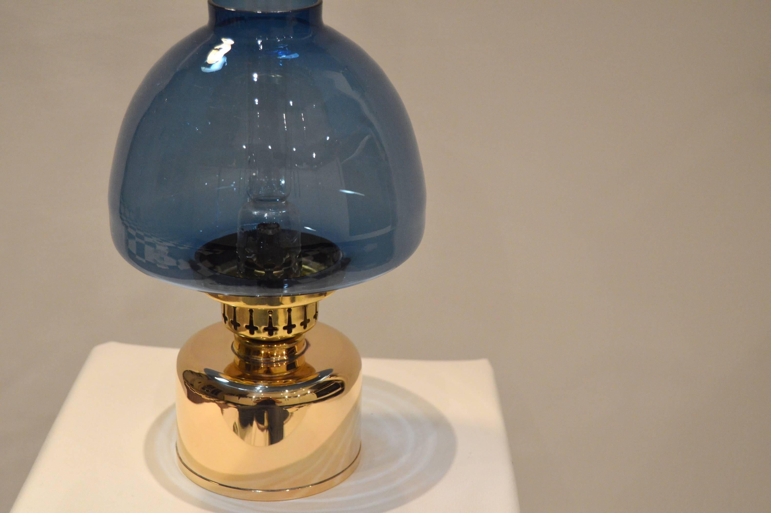 Elegant and rare kerosene lamp, even called oil lamp. Designed by Hans-Agne Jakobsson for his own company Hans-Agne Jakobsson AB in Markaryd Sweden.

- Blue glass and brass
- Patina on the brass
- The height below is given including the burner