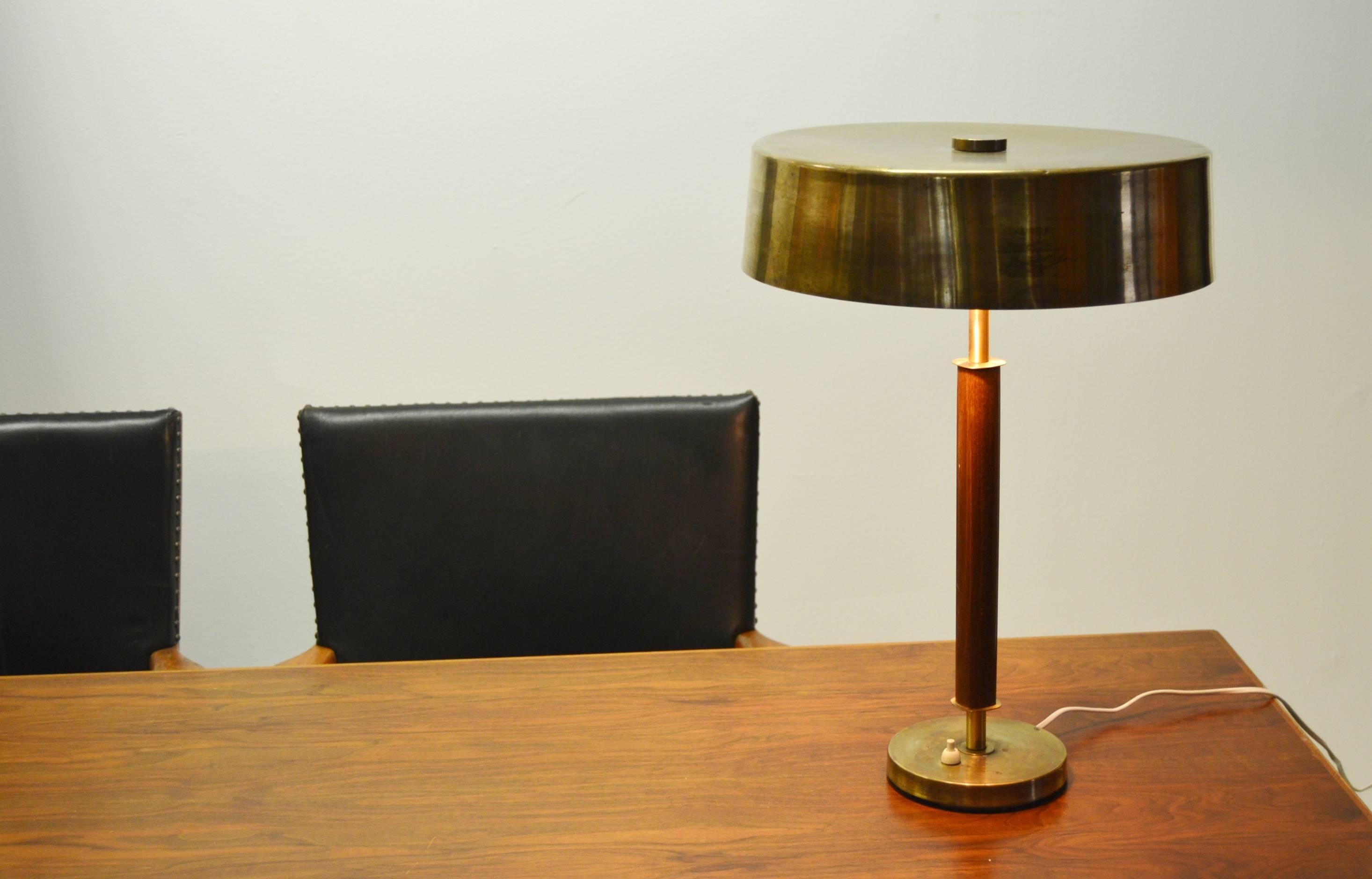 Heavy, solid and well-made. Larger than normal for this type of desk table lamp.
For us, unknown better manufacturer.
Brass and wood, most likely stained birch.
Signs of usage and minor traces of an old sticker on the lampshade, as shown in the