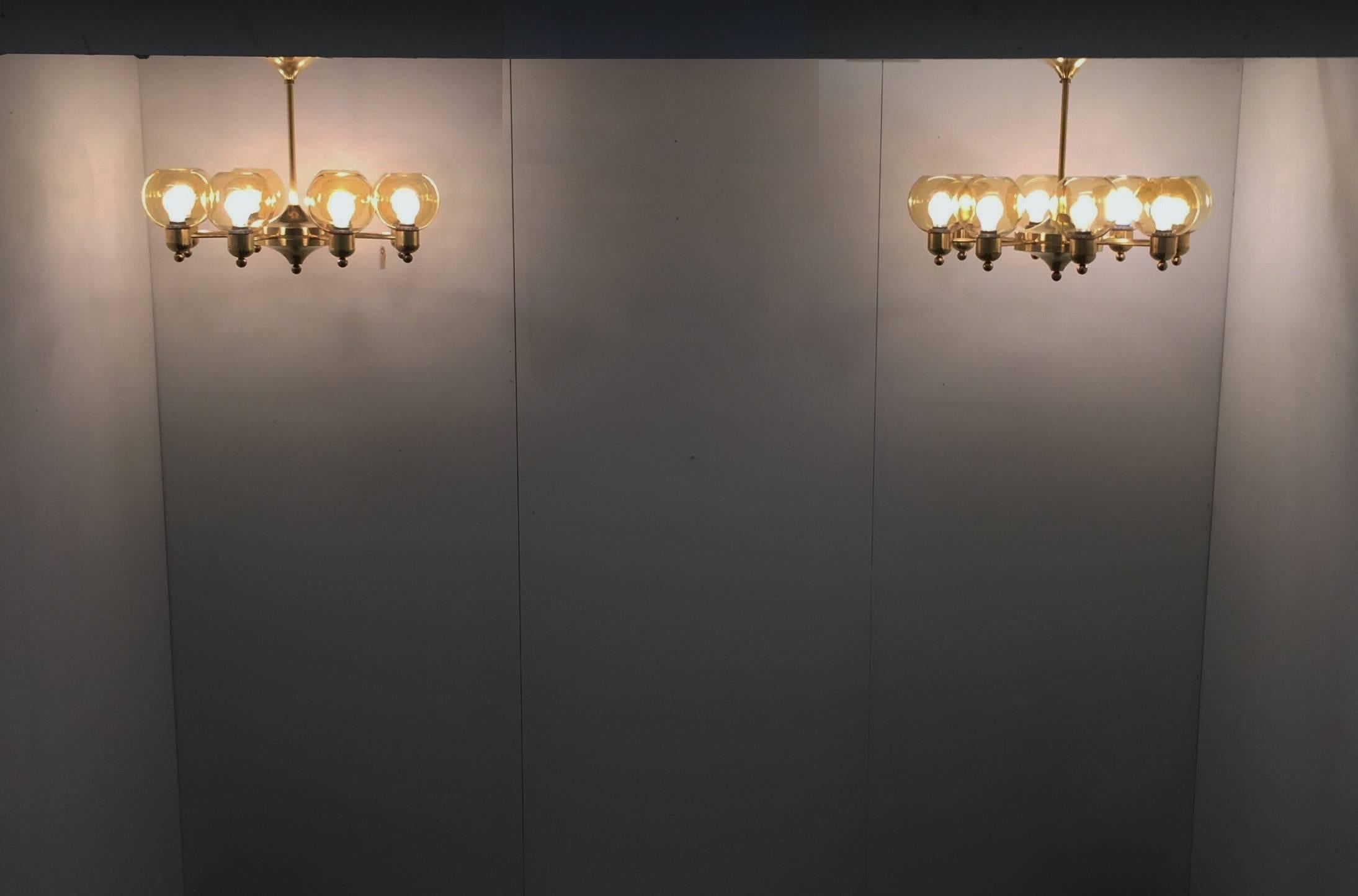 Set of two large chandeliers. Brass base and yellow toned handblown glass.
Eight glass globes on each lamp gives a bright good light.
The small plastic buds on bottom is there for the design.

Two extra globes is included as spare parts.