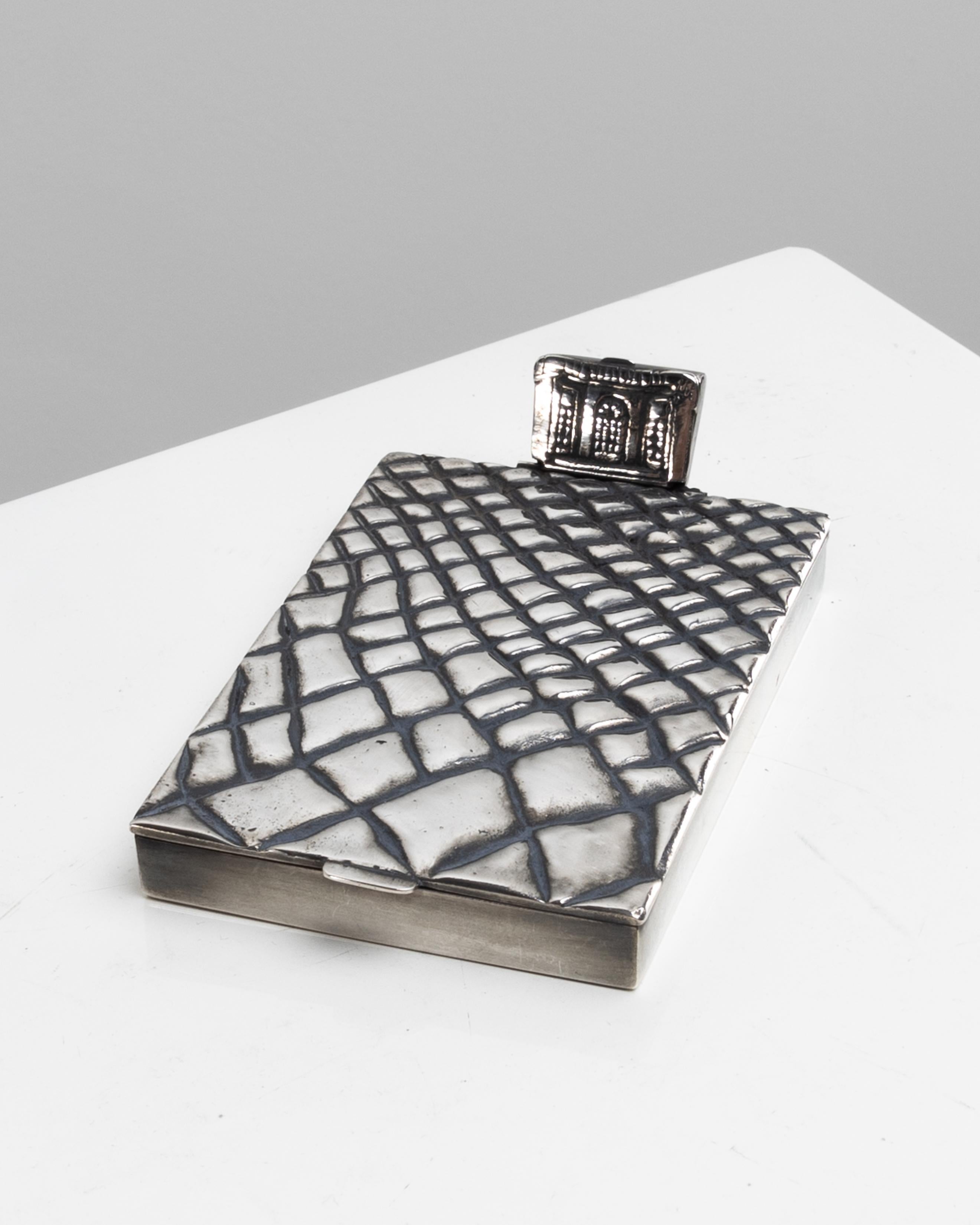 “Trianon” or “Les pavés du Roy”, silvered bronze compact by Line Vautrin.
Silver-plated bronze compact depicting the cobblestones of the Château de Versailles. On the upper part, a hinged powder compartment box recalling the facade of the