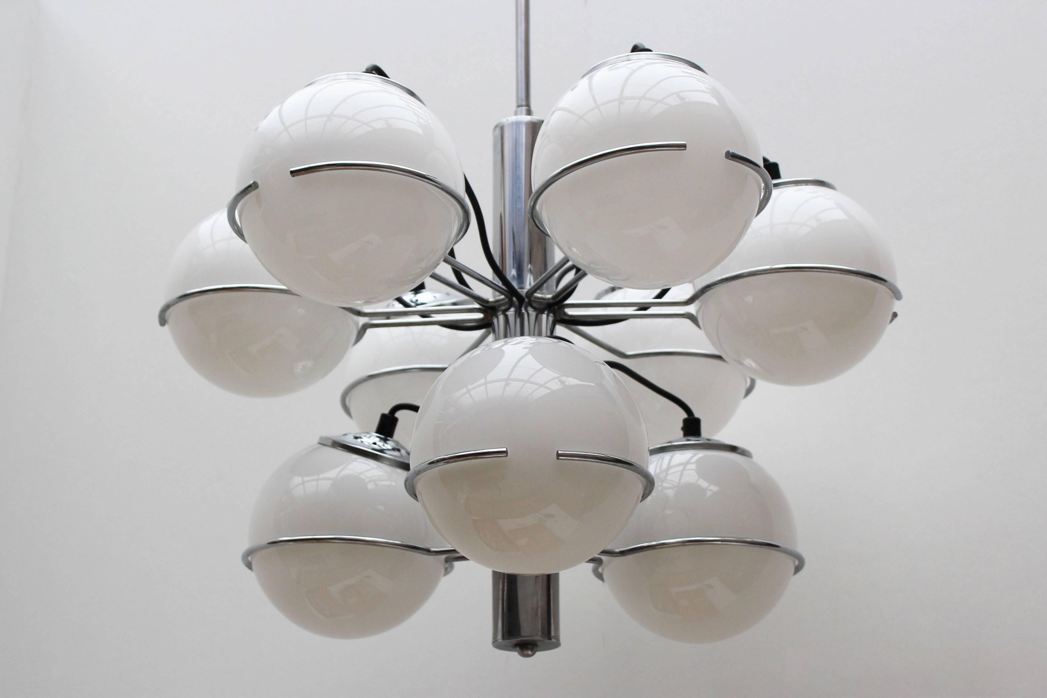 Midcentury Italian design chandelier by Targetti Sankey, 1970. The chandelier has a Minimalist chrome frame with nine opaline glass spheres. When lit the opaline spheres appear to float in the chrome rings.
When lit the opaline glass in combination