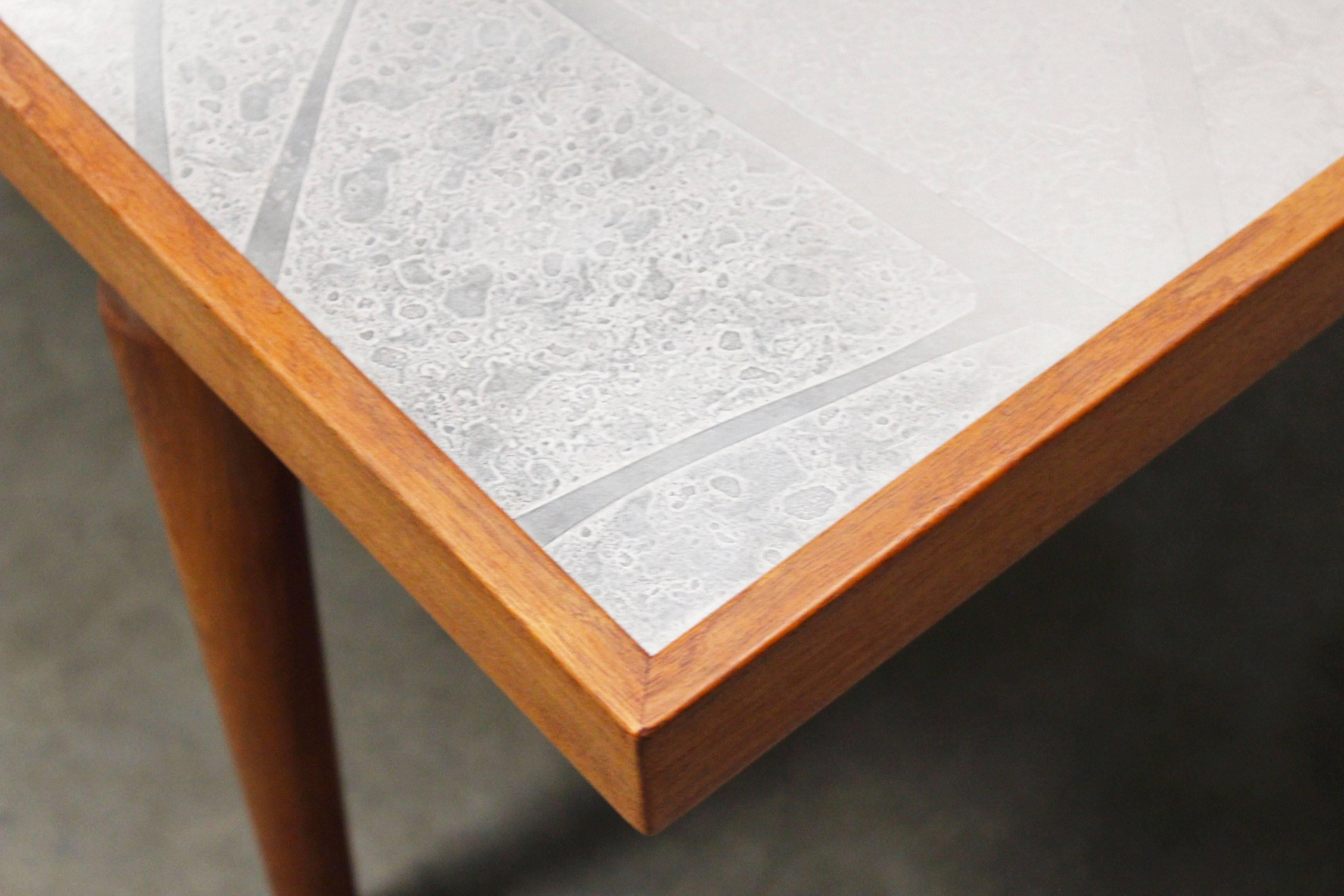 Cette table basse a été fabriquée et conçue par le designer allemand Heinz Lilienthal en 1970. Lilienthal était connu pour ses décorations murales faites de métal, de bois et de béton. Le plateau de cette table basse présente un motif réalisé par la