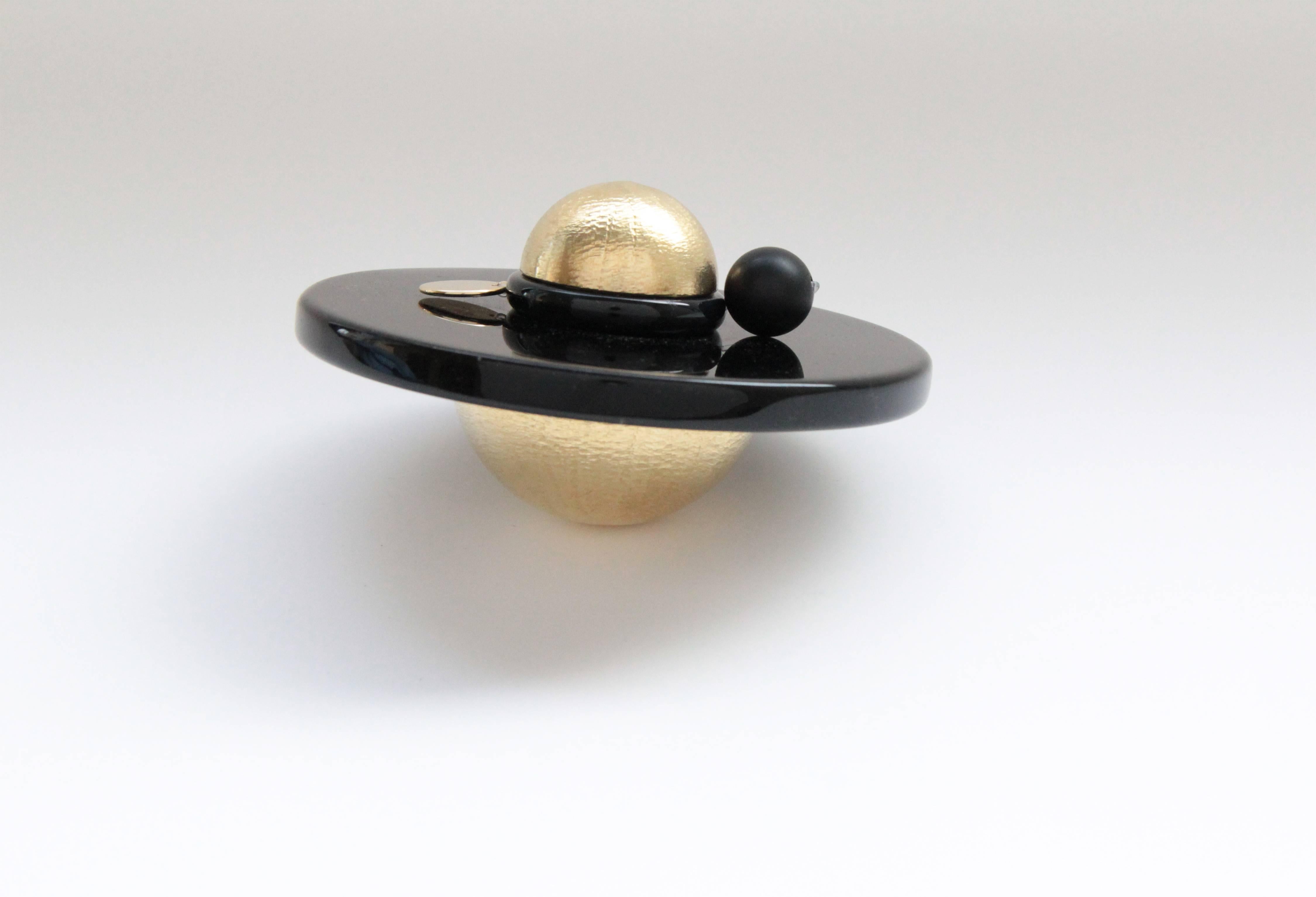 'Saturno' is a handcrafted contemporary design object inspired by the cosmos and the mysterious planet, Saturn. Made from hand etched solid cast brass, black obsidian glass, and set with glass beads, black stone and metal disc. 'Saturno' is a