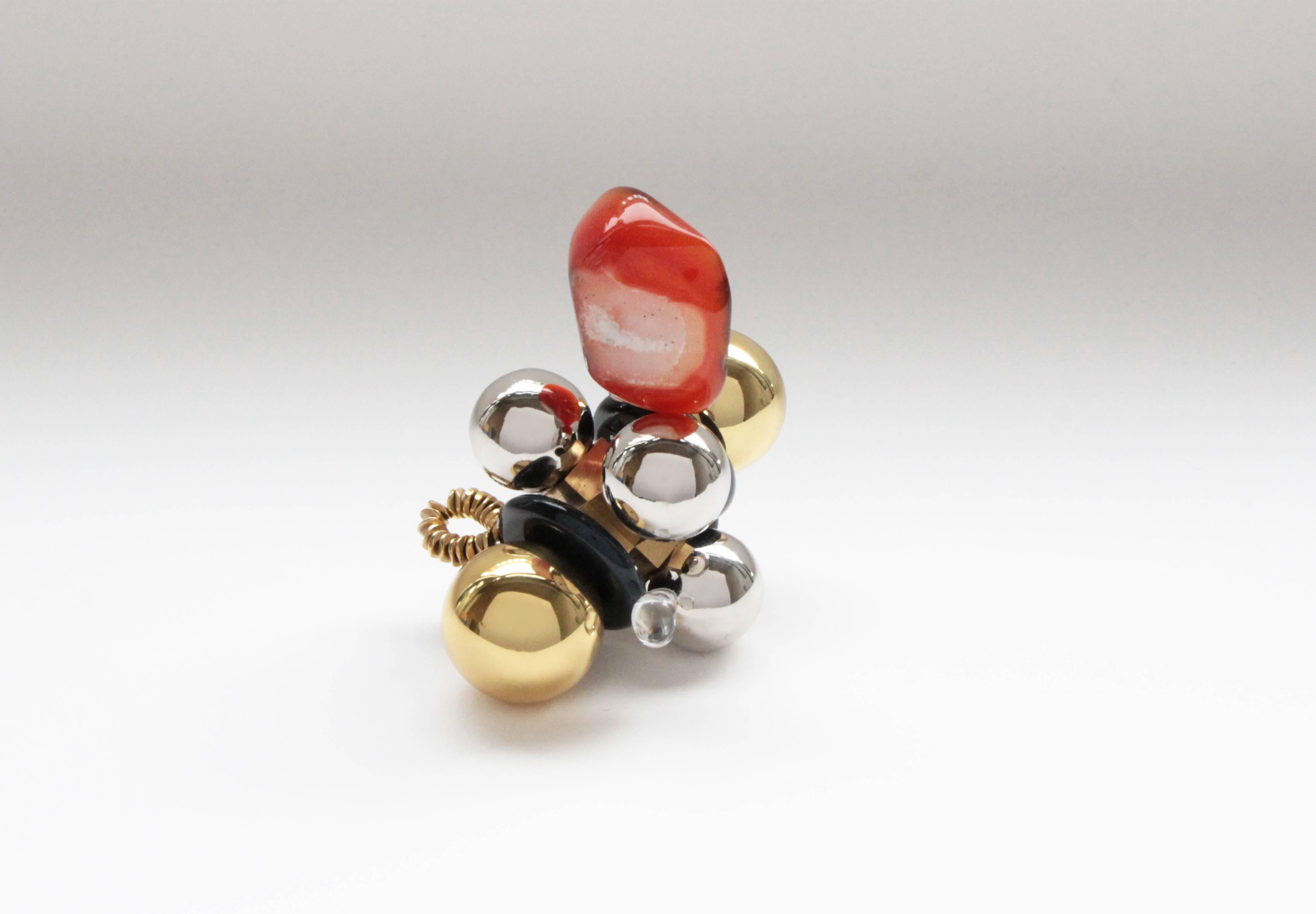 'Roso' is handcrafted from polished and sealed cast brass, nickel-plated spheres, red agate onyx stone, glass and brass beads, with clear quartz and black stone. This contemporary object makes for an ideal paperweight or small sculpture curiosity.