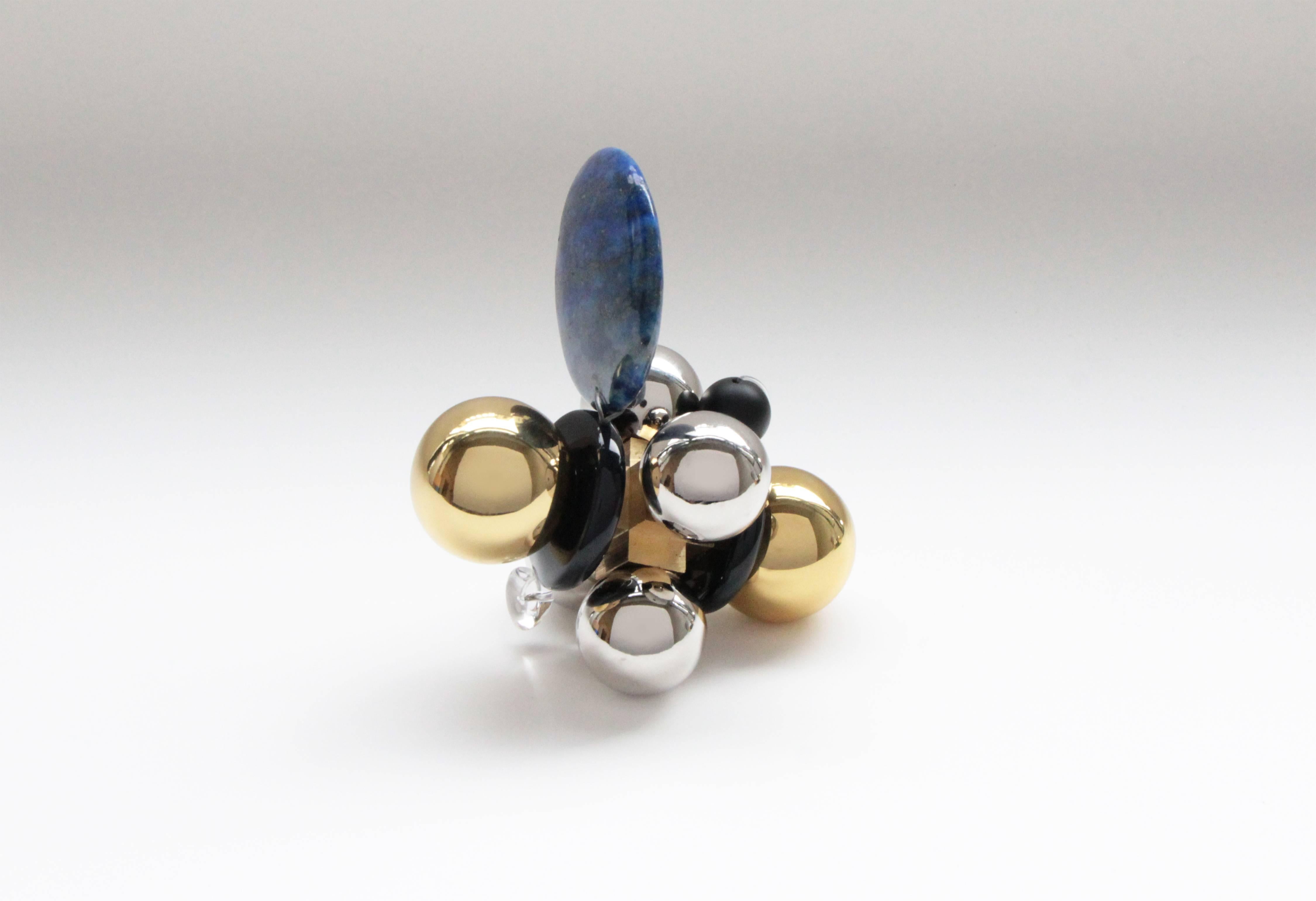 'Belu' is handcrafted from polished and sealed cast brass, nickel-plated spheres, blue lapis lazuli stone, glass beads, and clear quartz with black stone. This contemporary object makes for an ideal paperweight or small sculpture curiosity. Each one