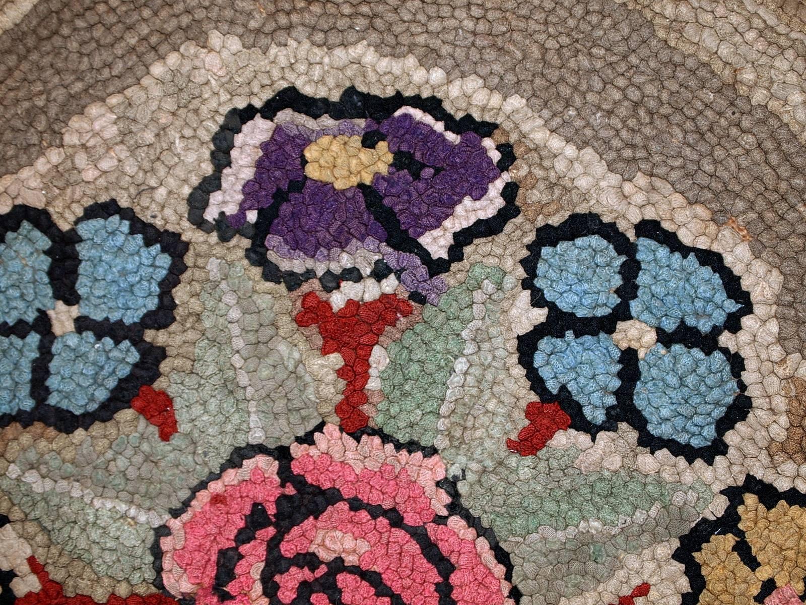 Handmade antique American hooked rug in good condition. The rug is in round shape. Beautiful colorful floral medallion surrounded by a multiply borders of different shades from grey to brown. The rug is from the beginning of 20th century and in